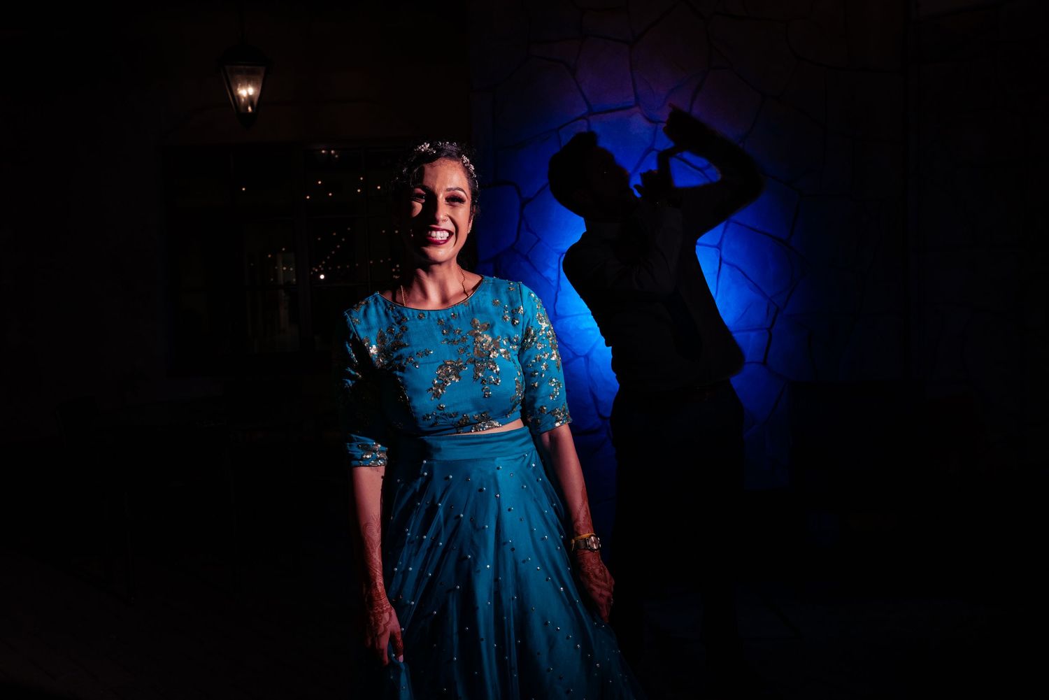 A person in a blue dress performs on stage with dramatic lighting and dark background.