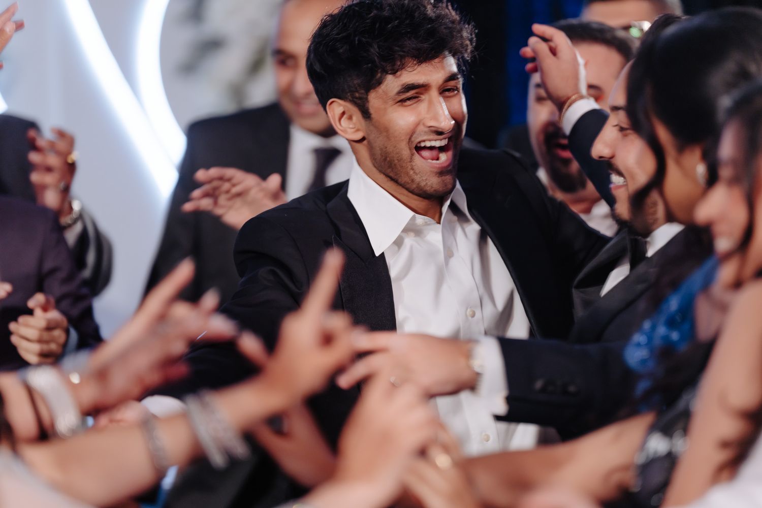 Joyful wedding celebration with guests dancing and celebrating in a modern venue.