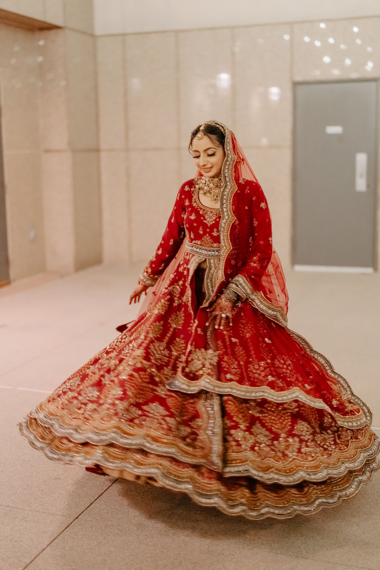 Beautiful red and gold traditional Indian bridal lehenga dress displayed in a twirling motion on a light floor.