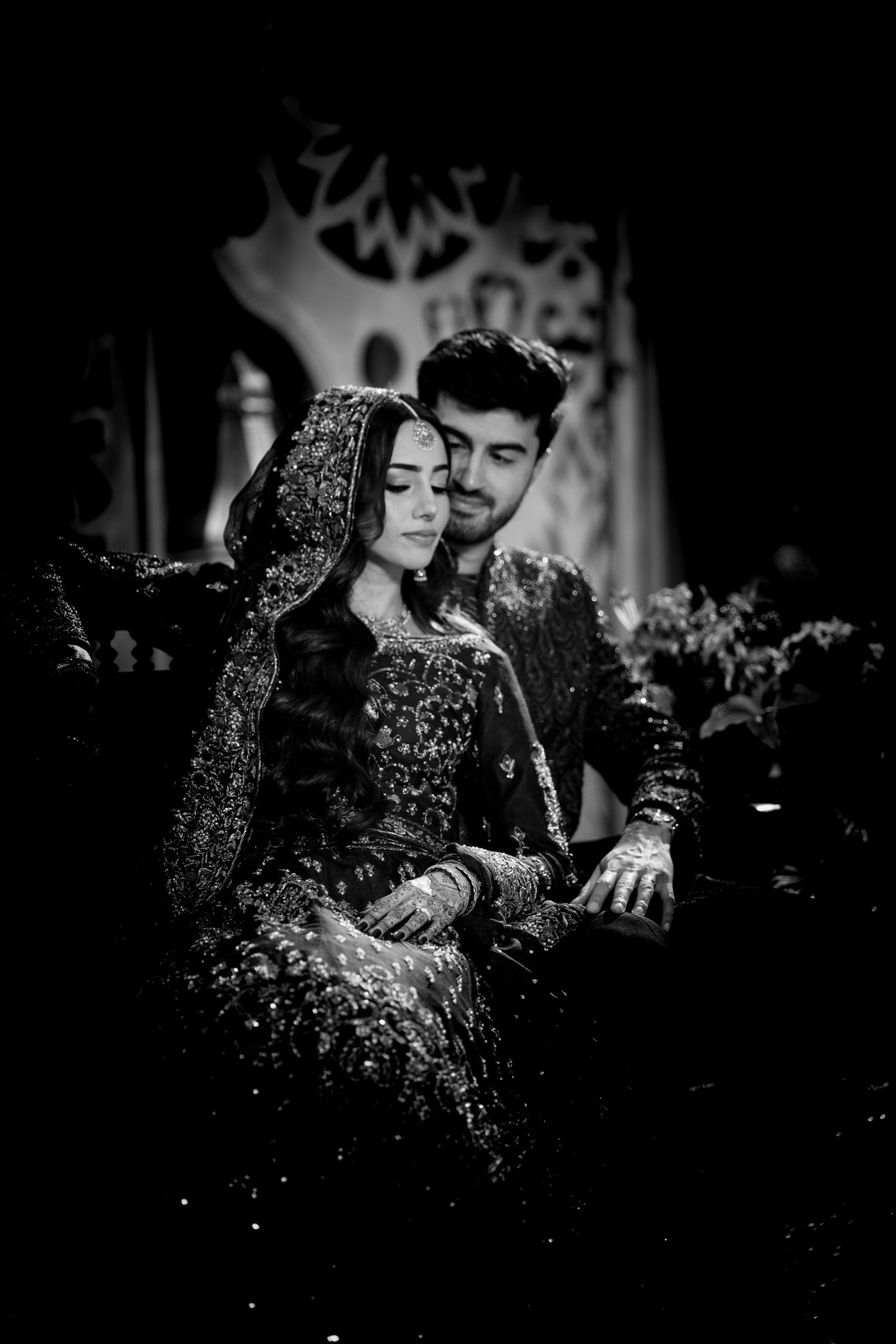 A couple in formal attire share an intimate black and white moment at an evening event.