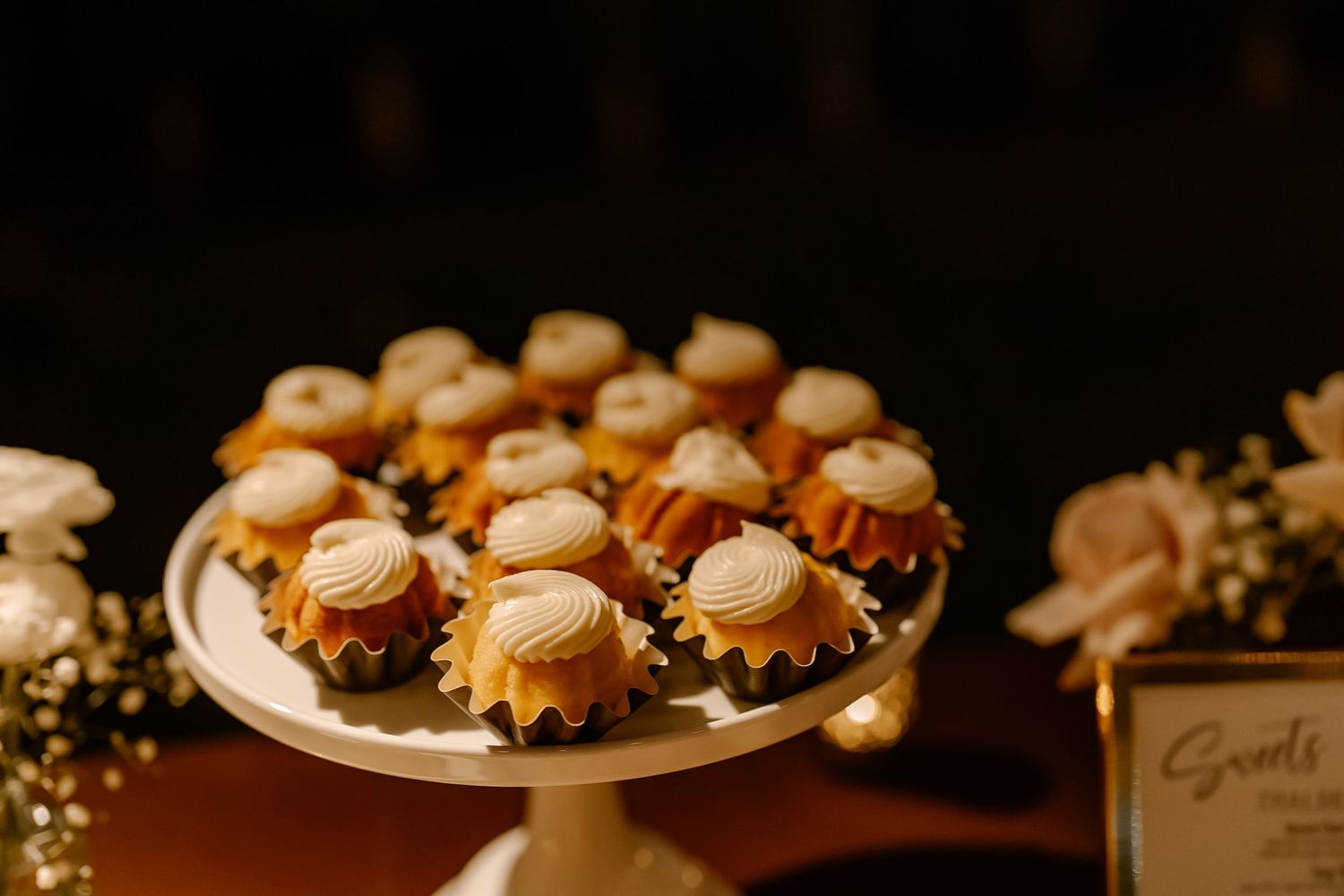 Elegant dessert display featuring miniature pastries and cupcakes arranged on white plates at a catering event.