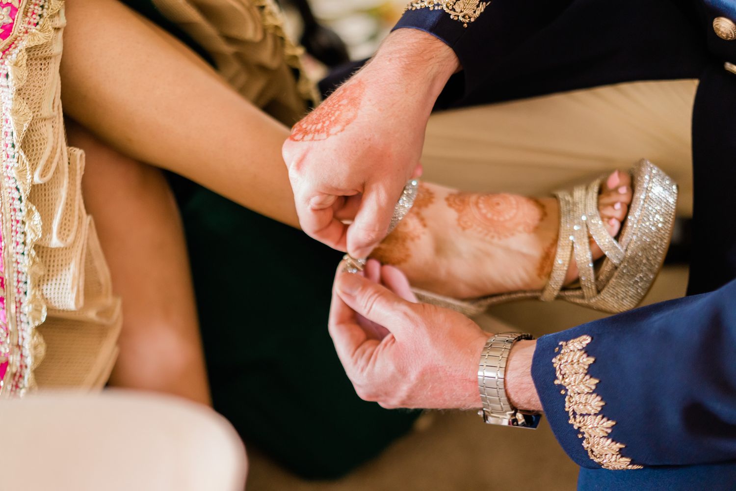 Wedding ceremony details showing hands exchanging rings with rose petals scattered on the surface.