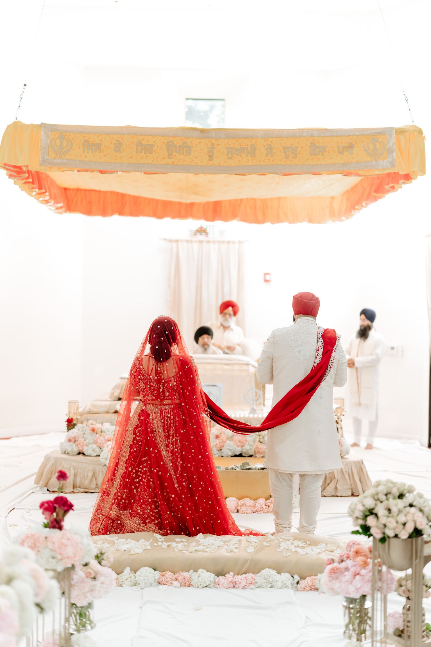 Wedding ceremony setup with red and white decor under an elegant canopy with floral arrangements.