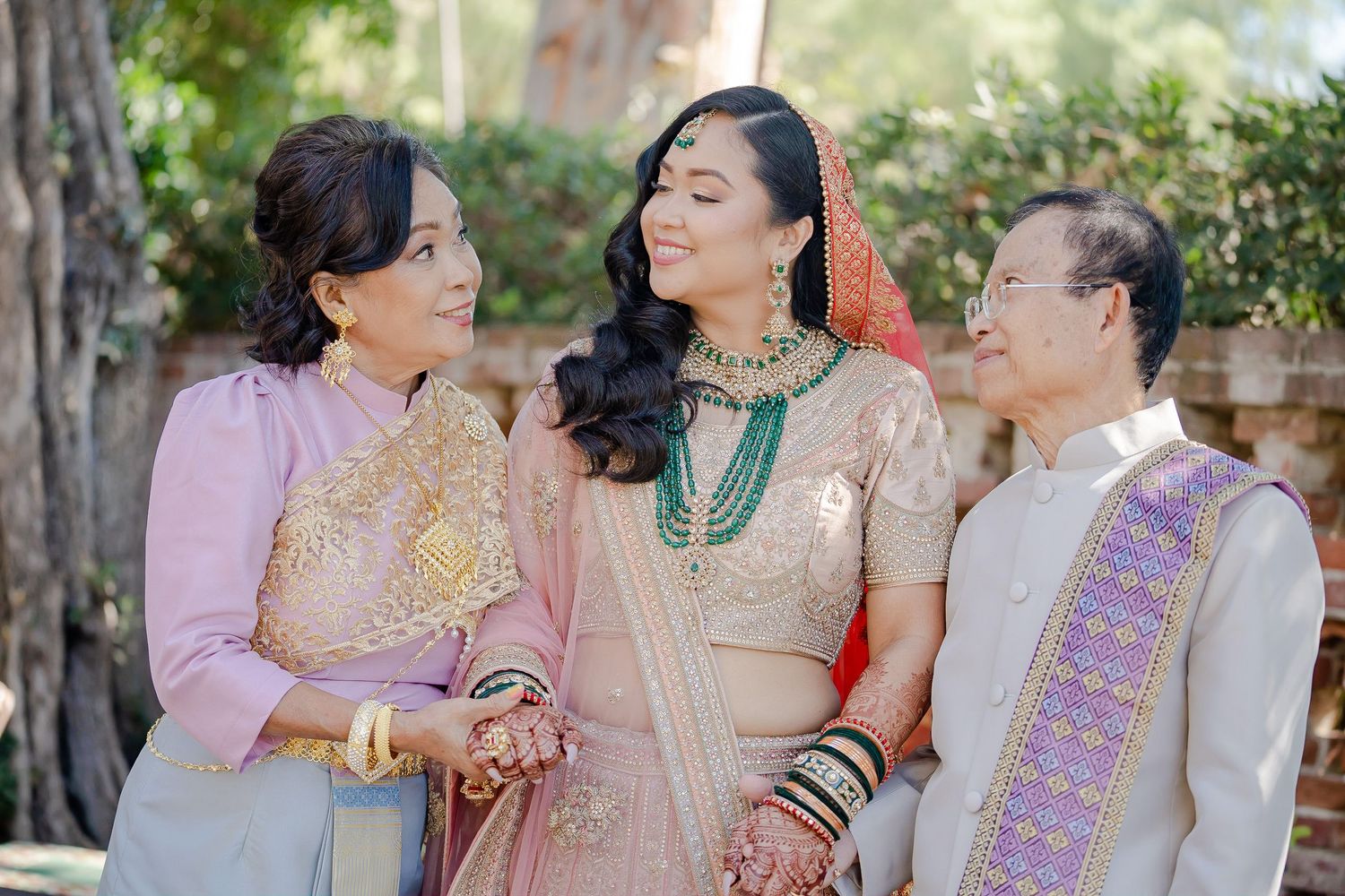 A group wearing traditional South Asian attire share joyful moments during a cultural celebration outdoors.
