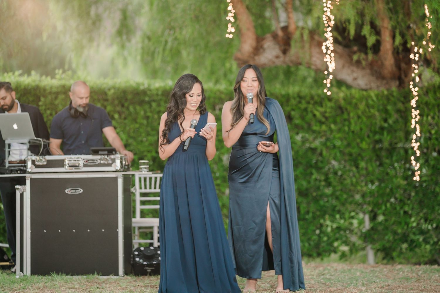 Wedding party members in navy blue attire stand together during an outdoor celebration.