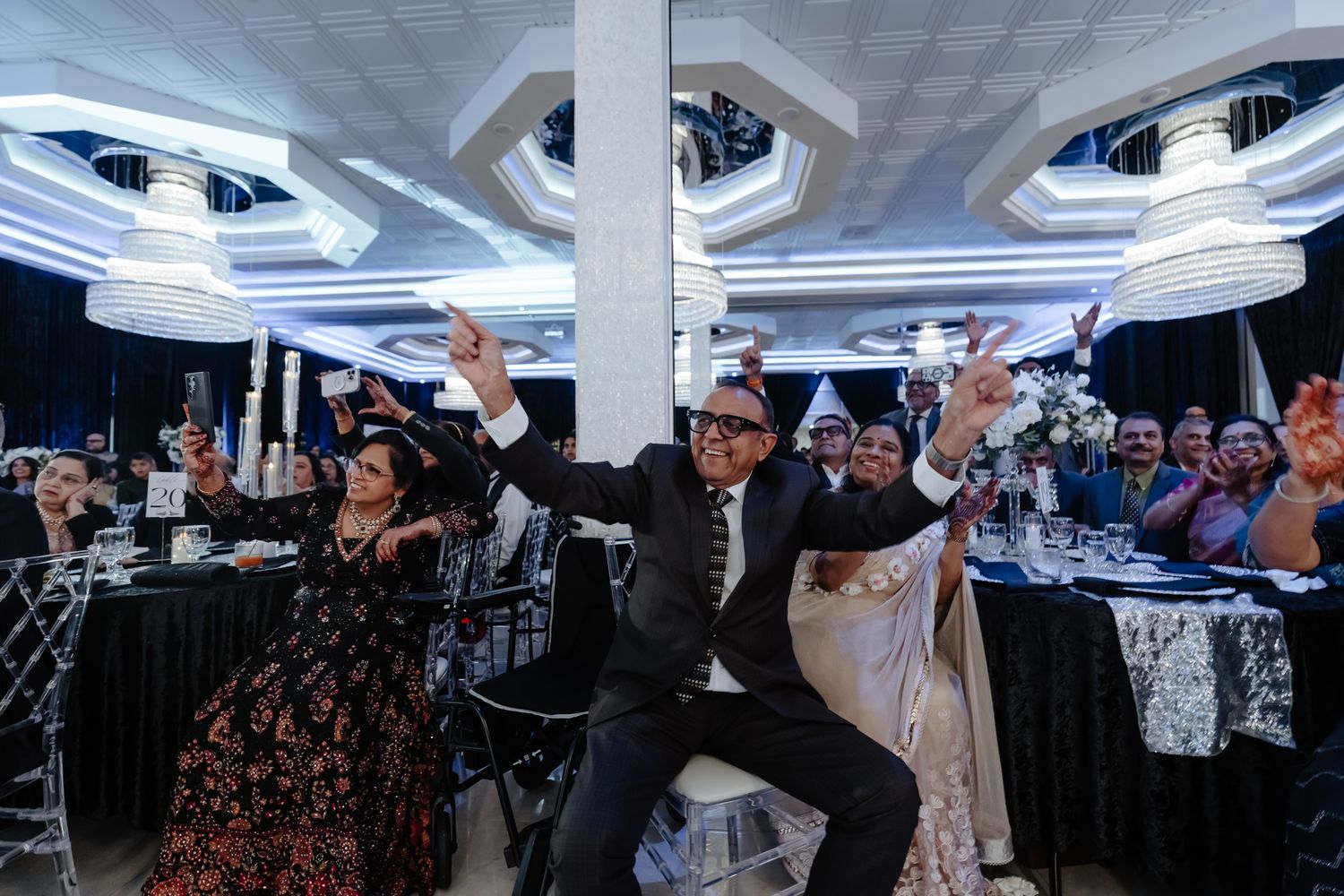 Guests enjoy dancing and celebrating at an indoor wedding reception with modern lighting.