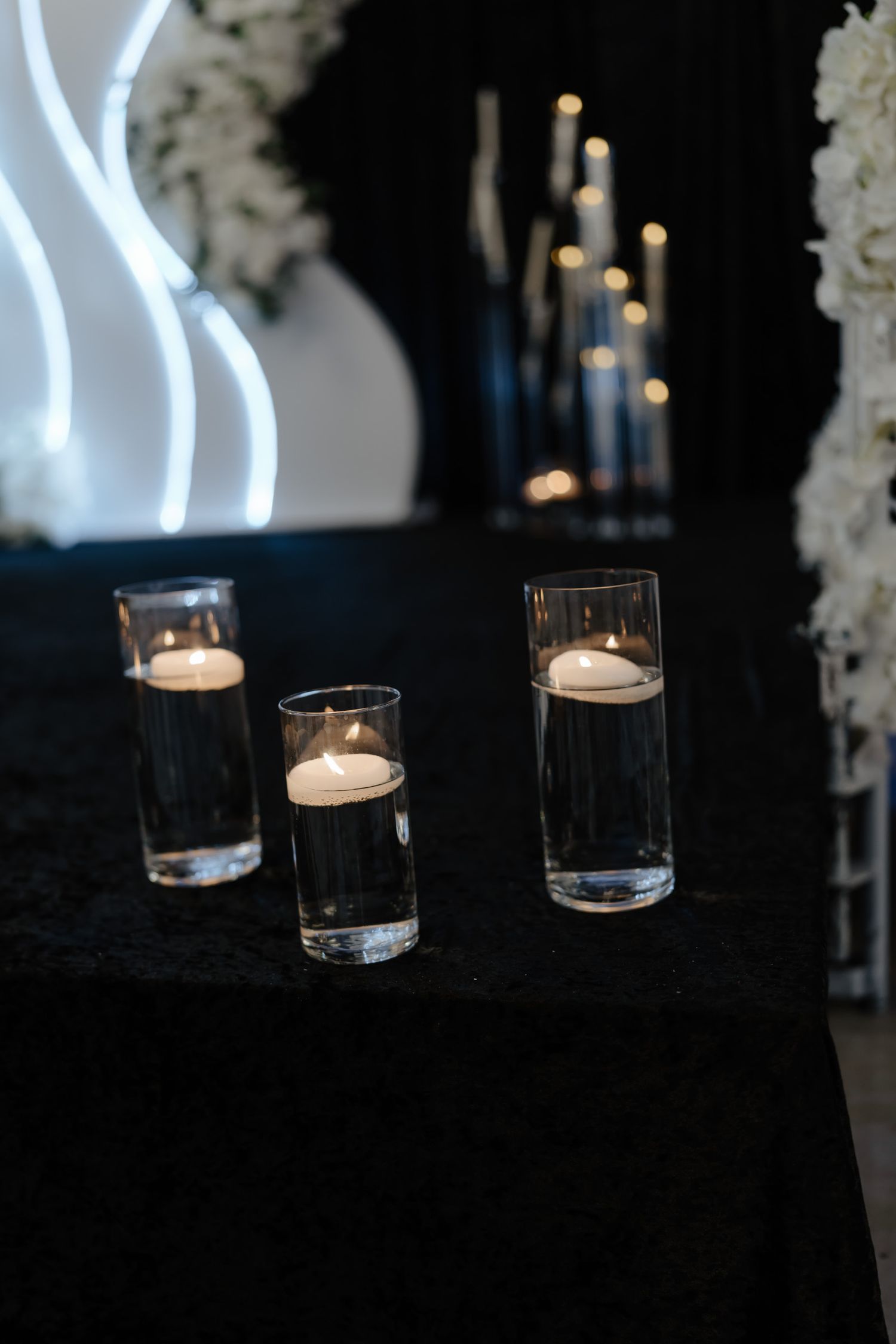 A sequence of glowing white candles in glass holders against a dark background creates an elegant ambiance.
