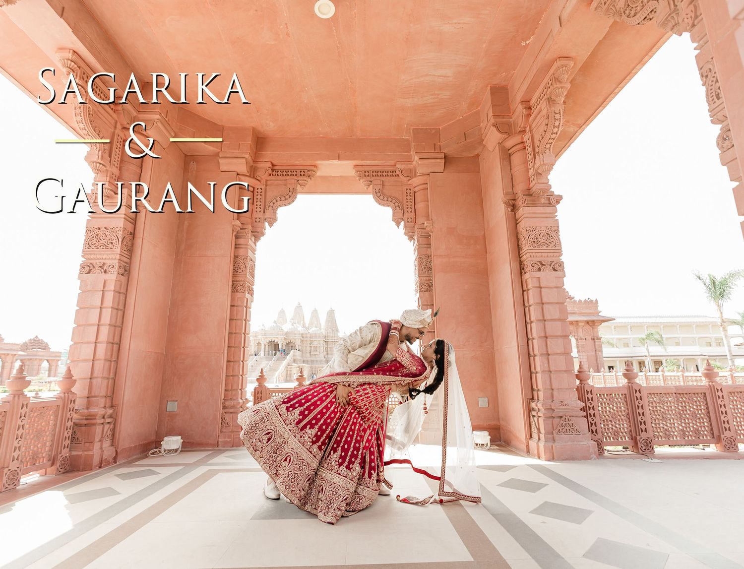 A person in a flowing red dress poses gracefully under ornate pink stone archways at Sagarika Palace in India.