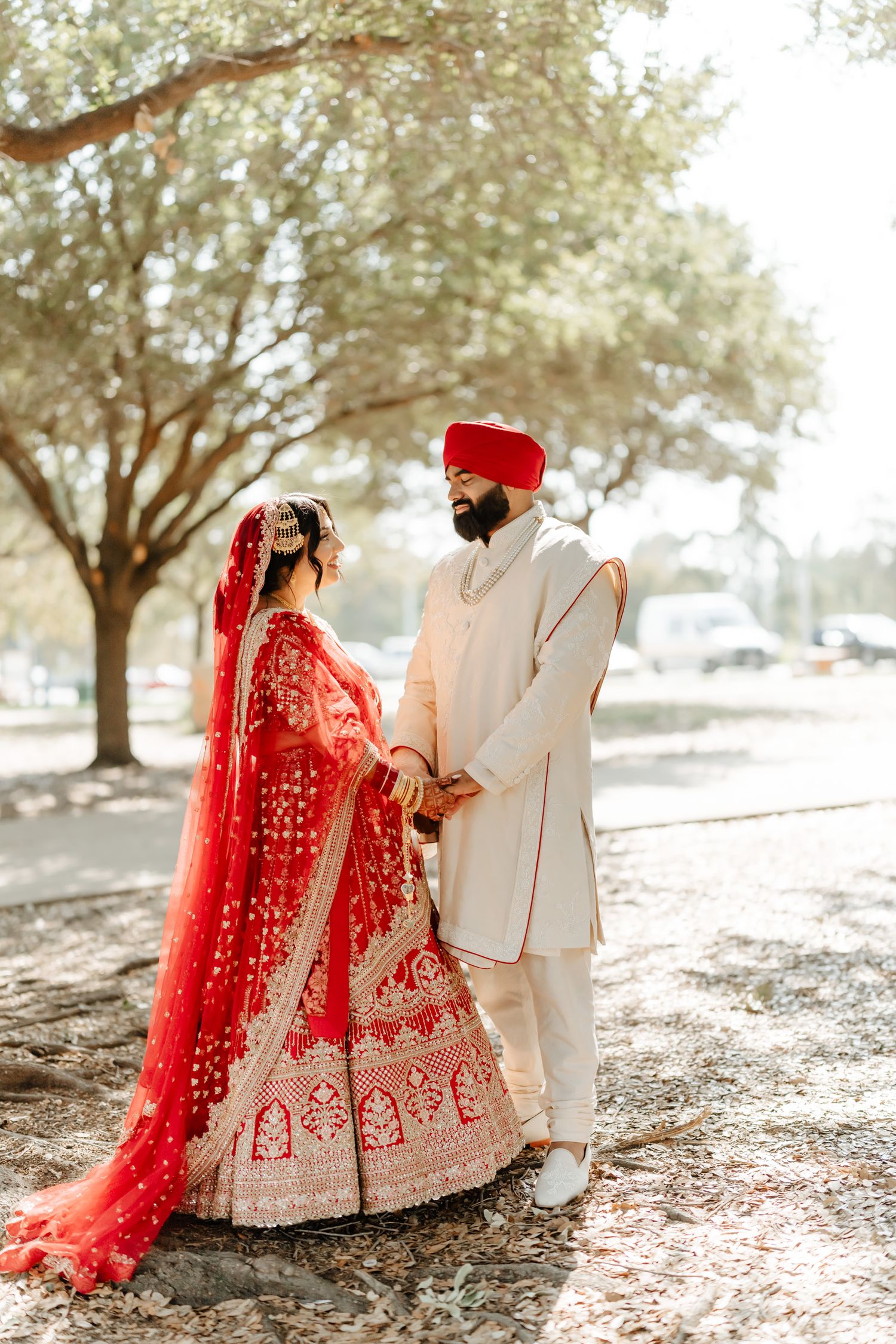 A series of romantic wedding photos showing a couple in traditional Indian attire with red lehenga against a sunlit outdoor setting.