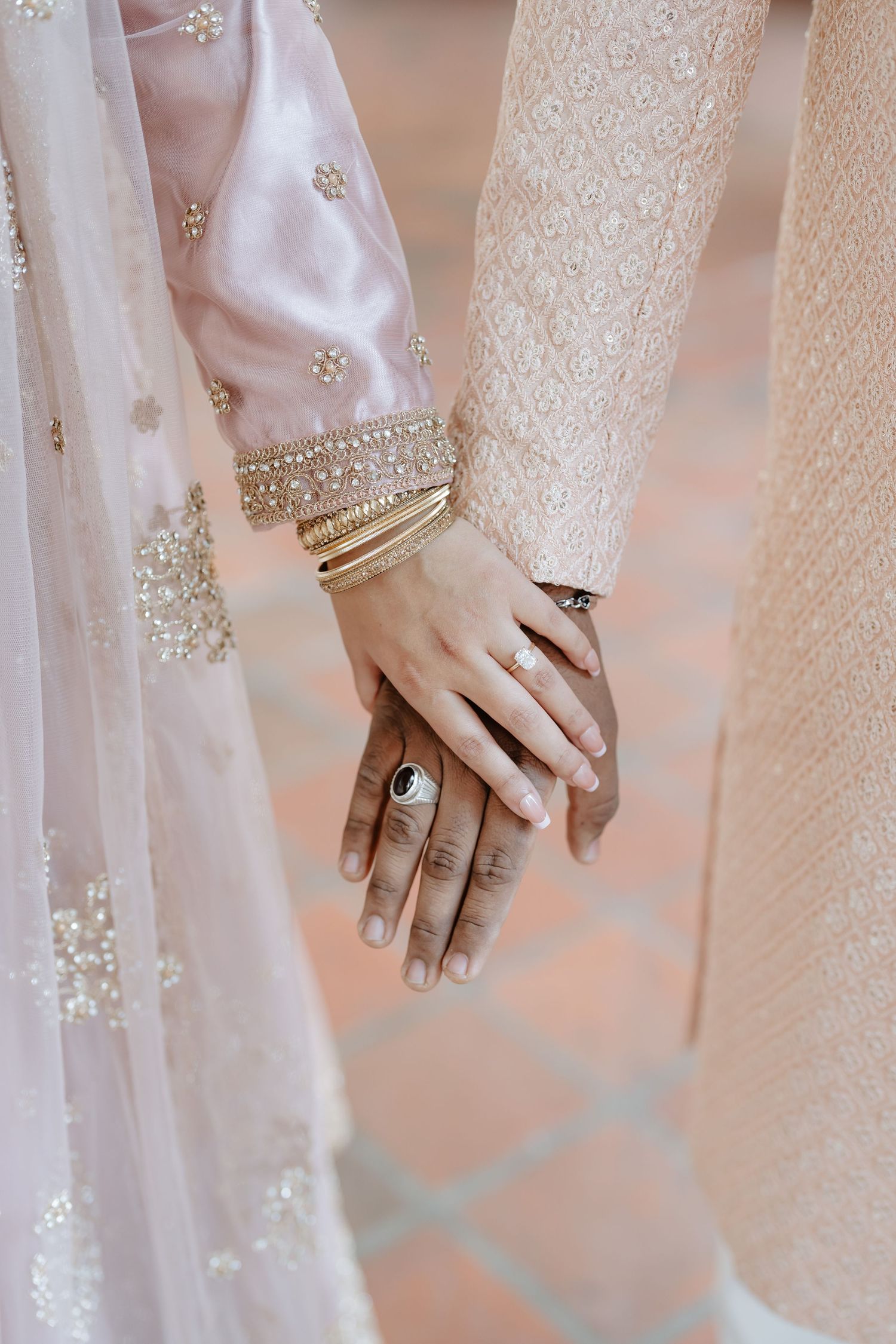Close-up of hands adorned with rings and bangles in traditional South Asian wedding attire.