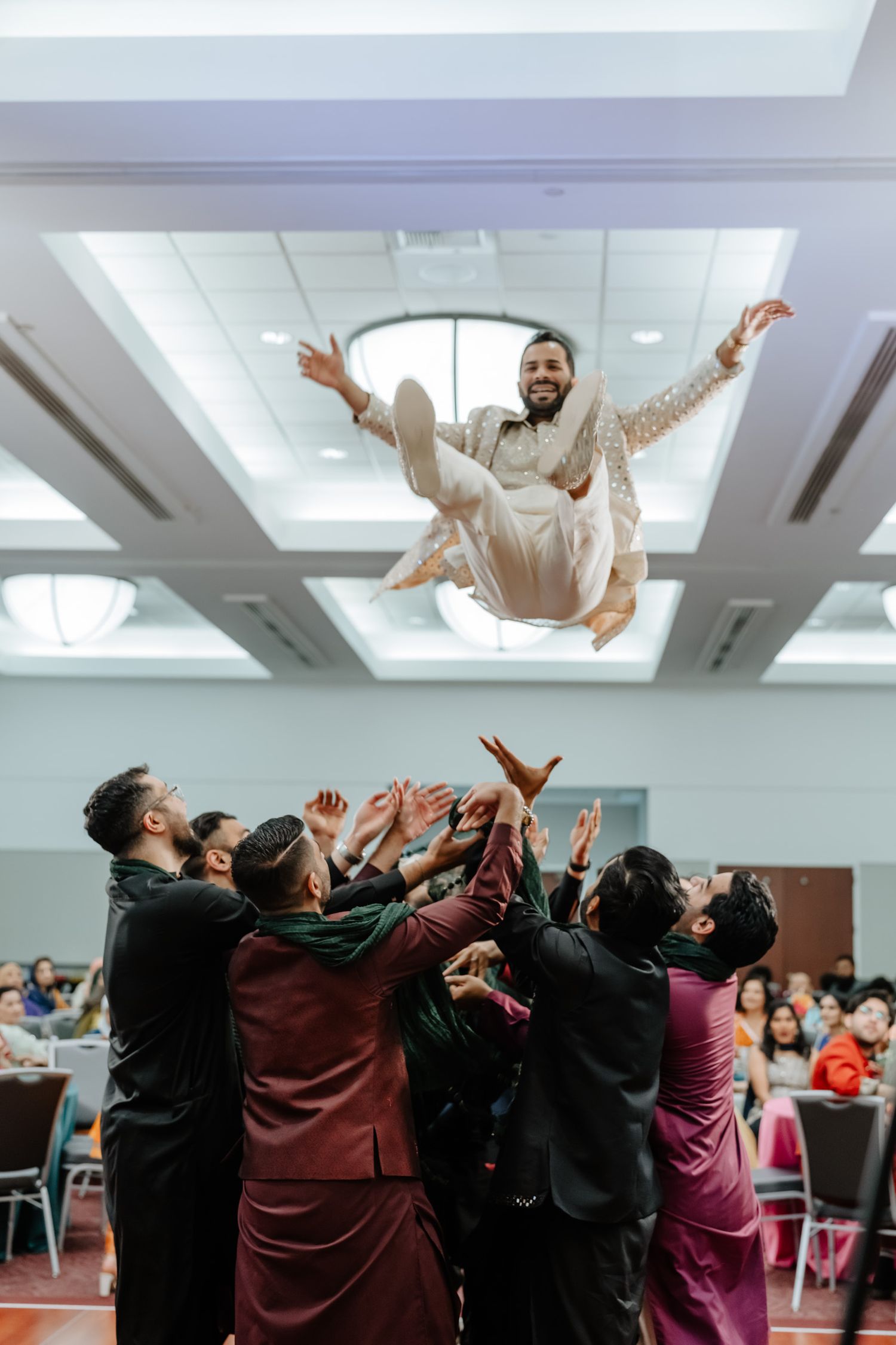 A group of people perform a trust fall exercise during a team building activity in an indoor space.