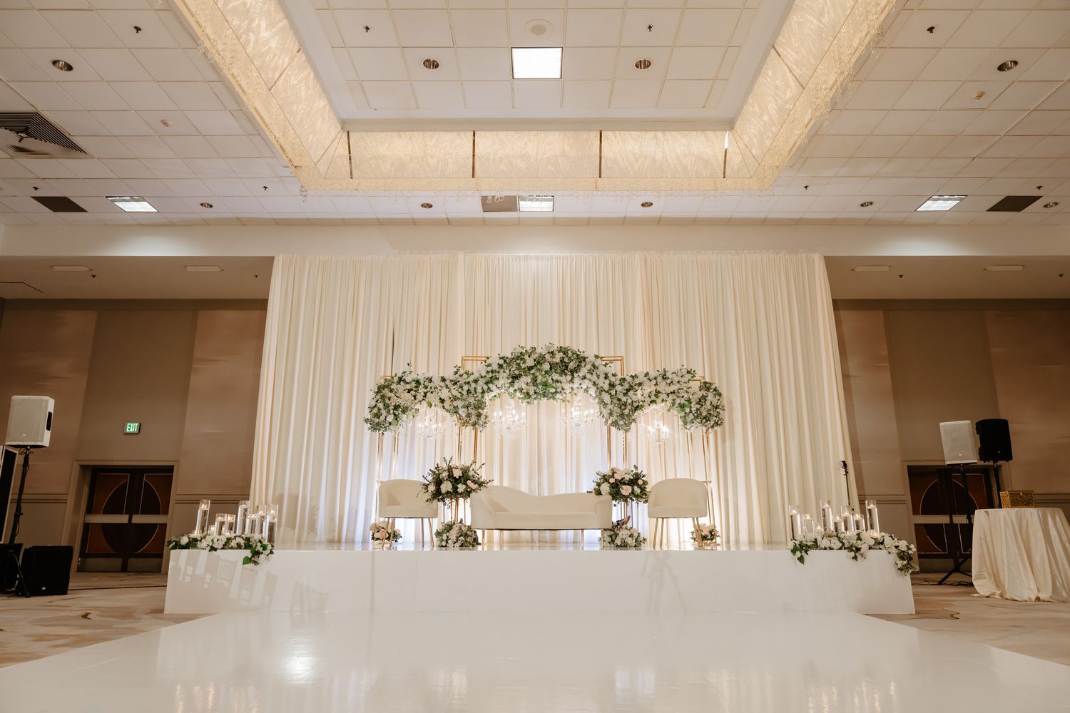 Modern white banquet hall decorated with minimalist floral arrangements and elegant draping.
