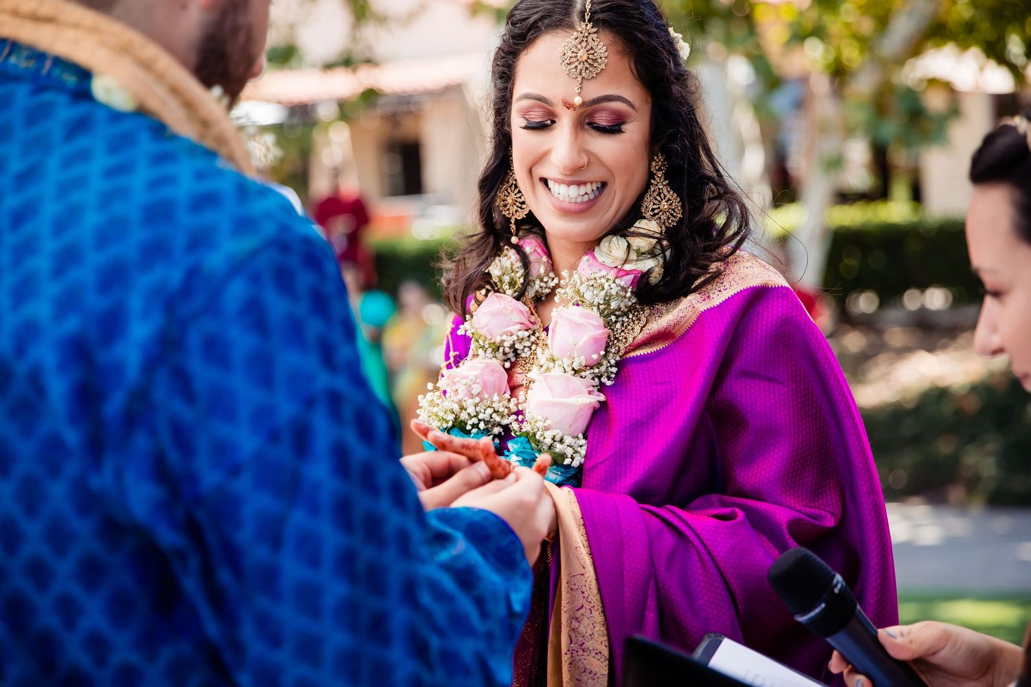 Traditional Indian wedding ceremony with vibrant purple attire and floral garlands during an outdoor celebration.