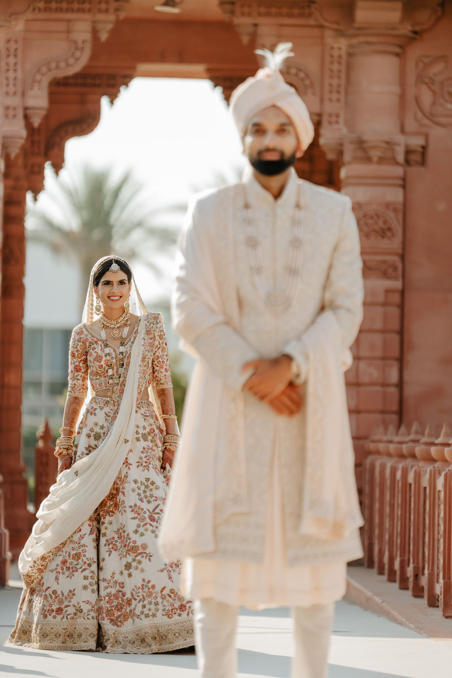 Elegant Indian wedding scene with ornate architecture and traditional white ceremonial attire.