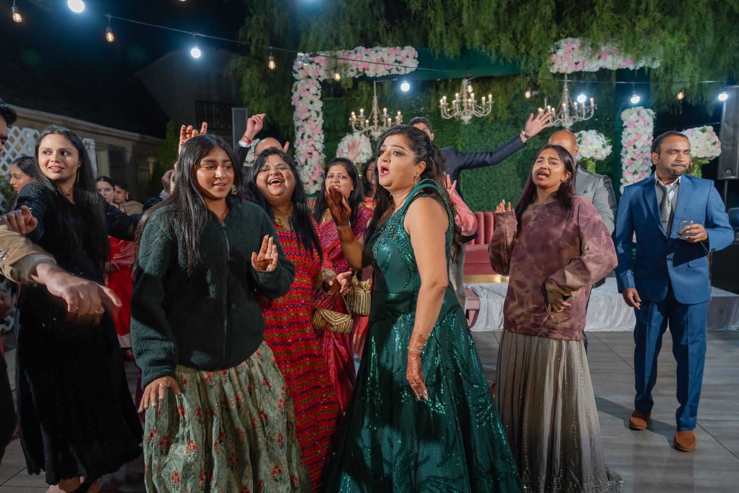 Wedding party and guests laughing and celebrating during outdoor nighttime reception.