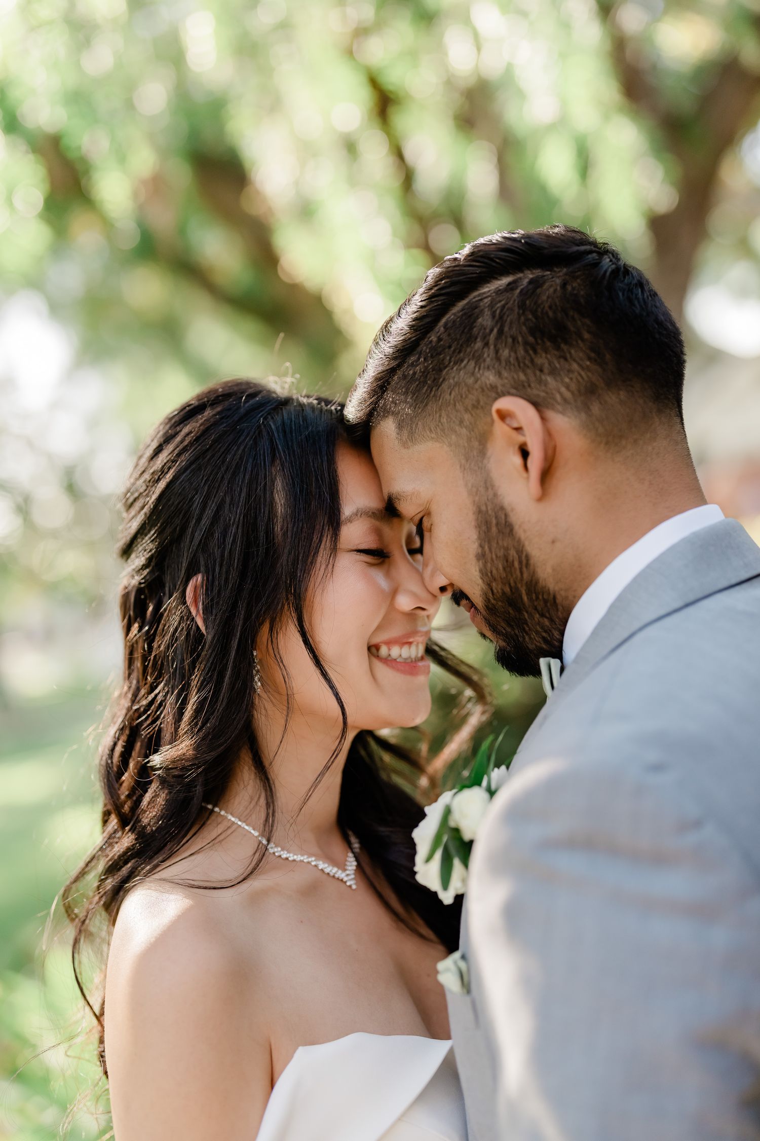 A tender moment between newlyweds sharing an intimate embrace in a sunlit garden setting.