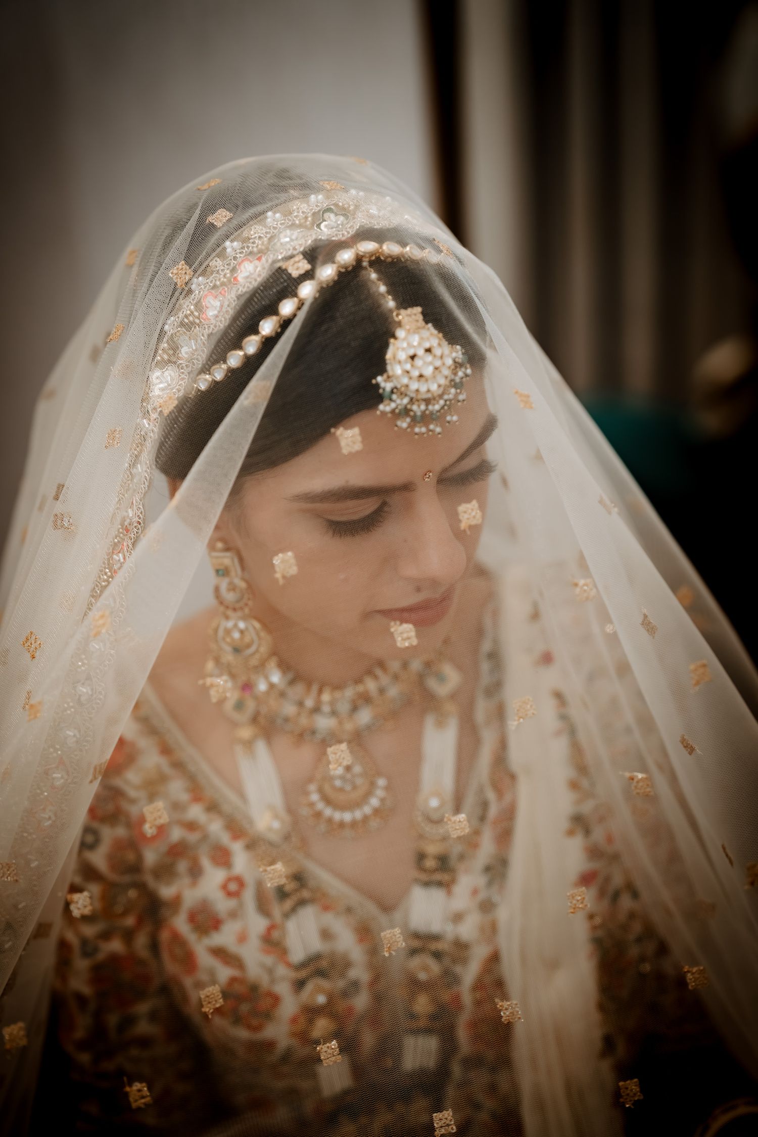 Traditional Indian bridal attire with intricate jewelry and embroidery captured in soft lighting.