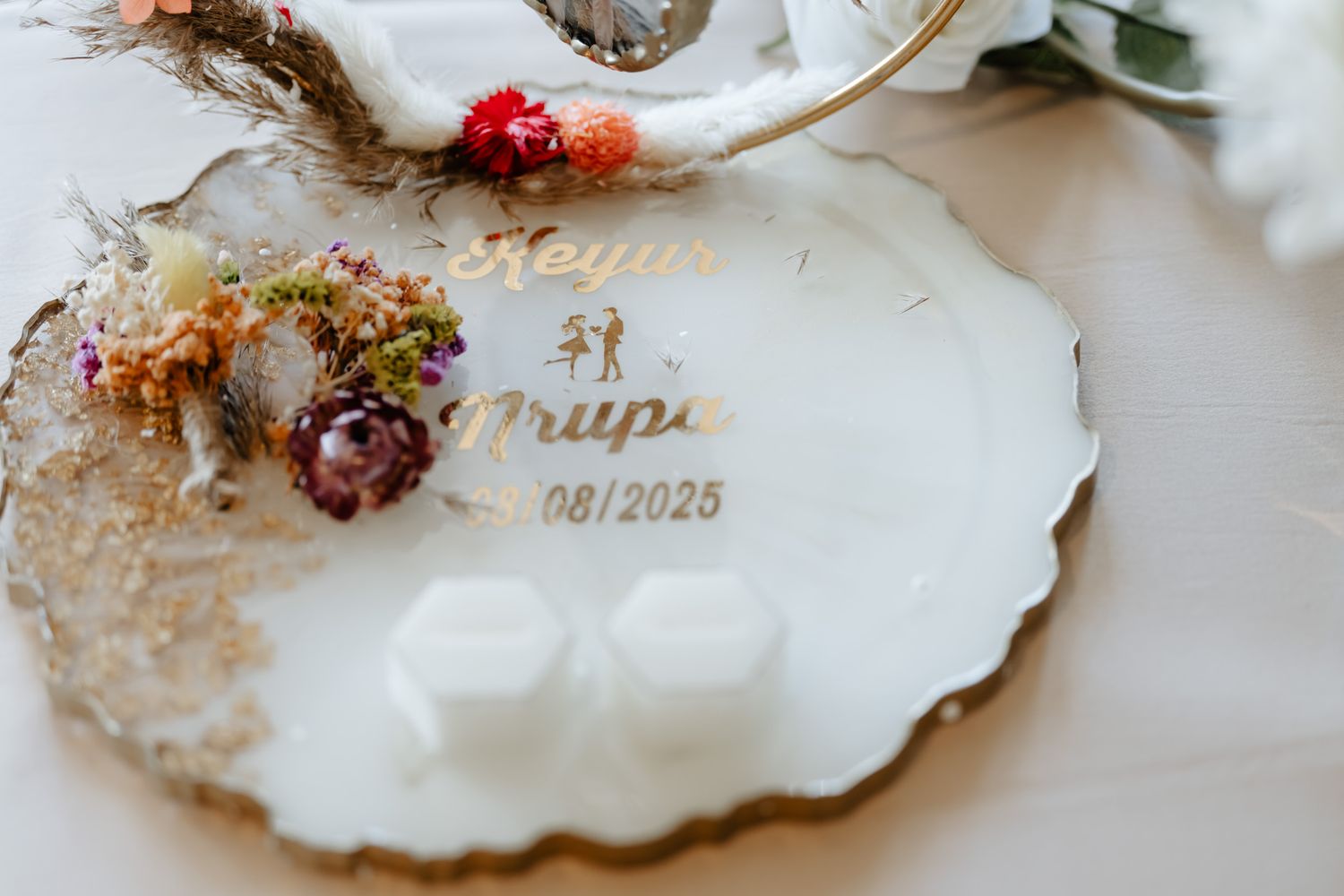 Close-up of decorative wedding invitation shell with dried flowers and gold accents.