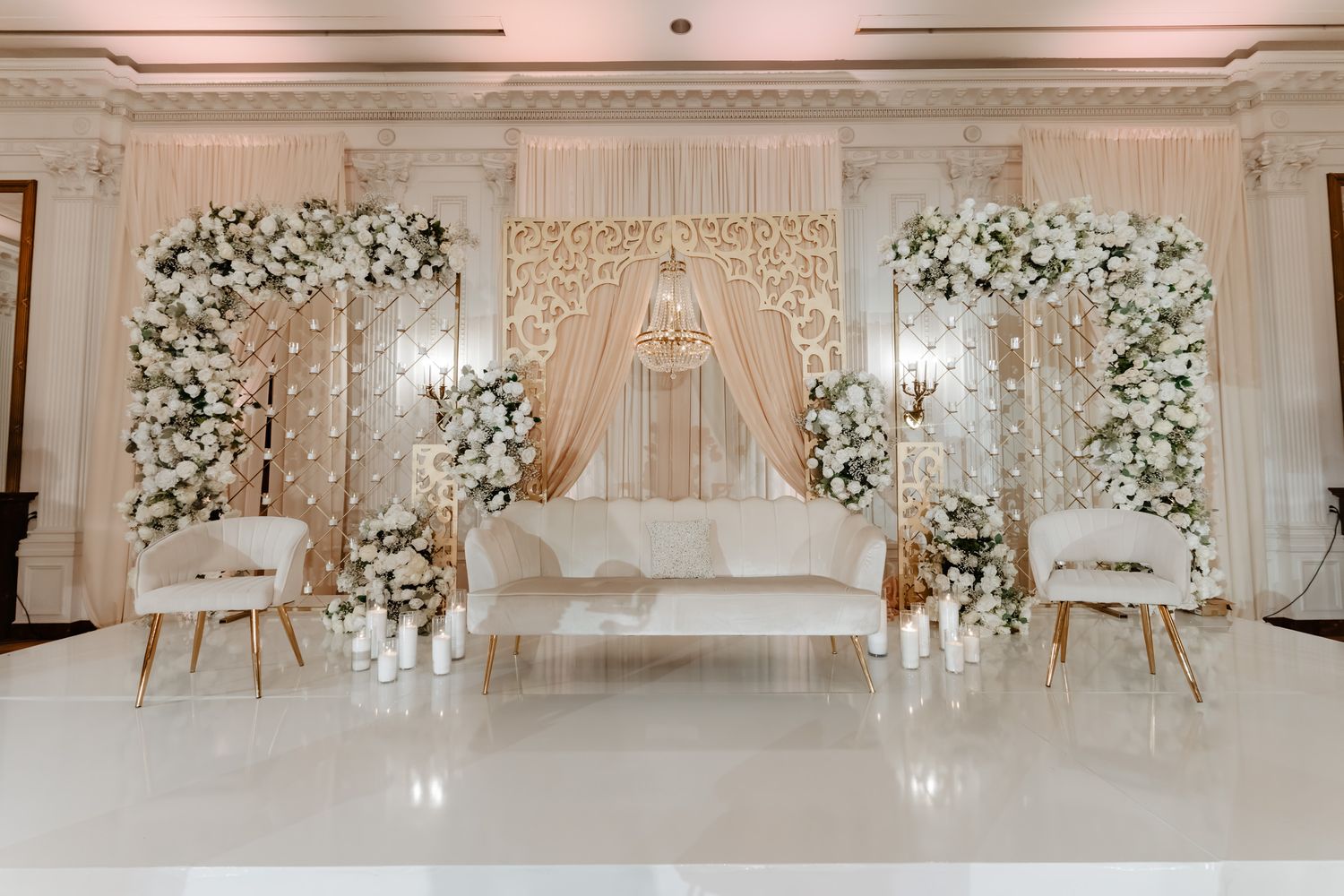 Luxurious wedding venue decorated with white floral arrangements and crystal chandeliers.