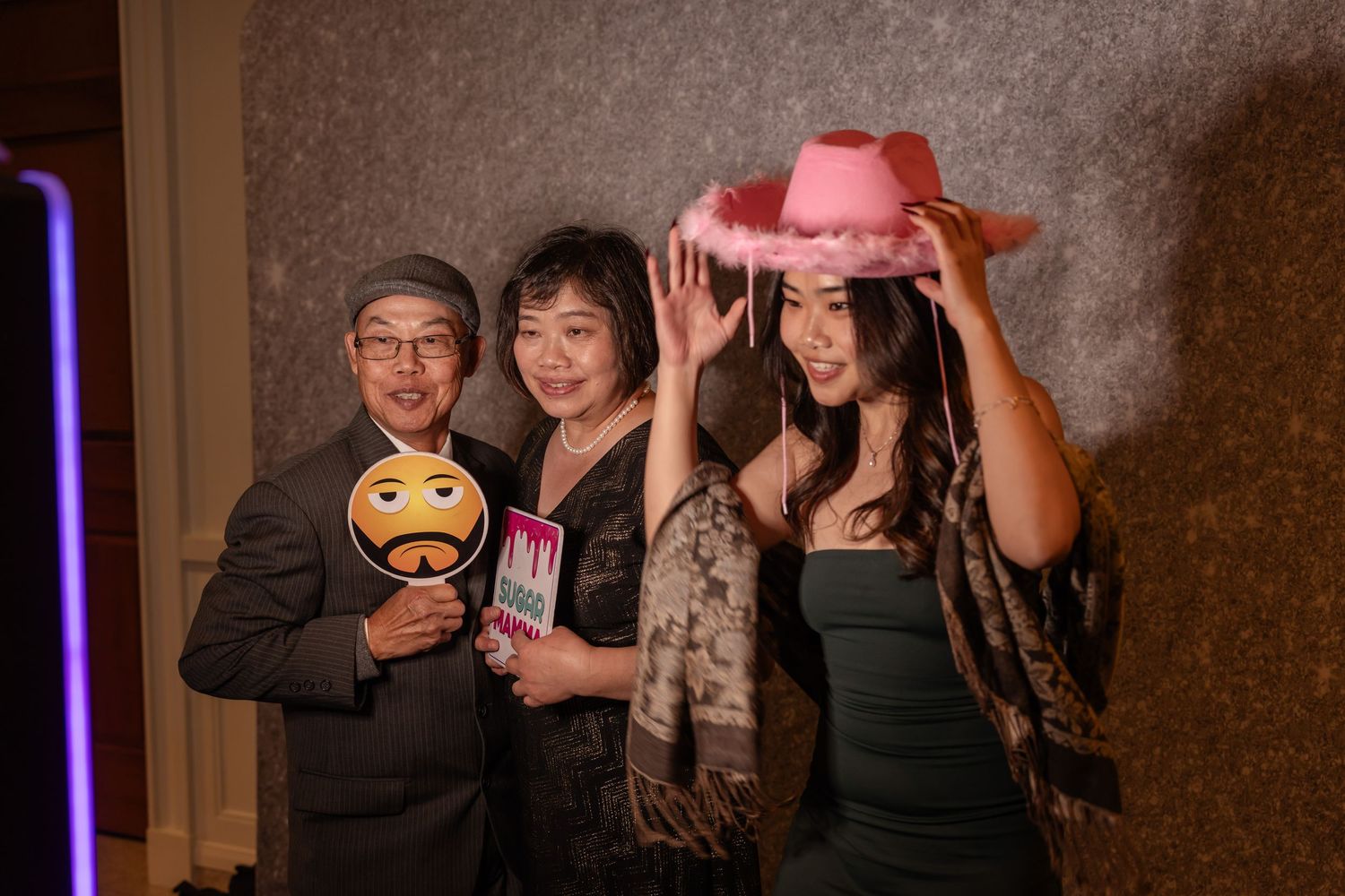 Wedding guests having fun with props and poses in a photo booth setup.