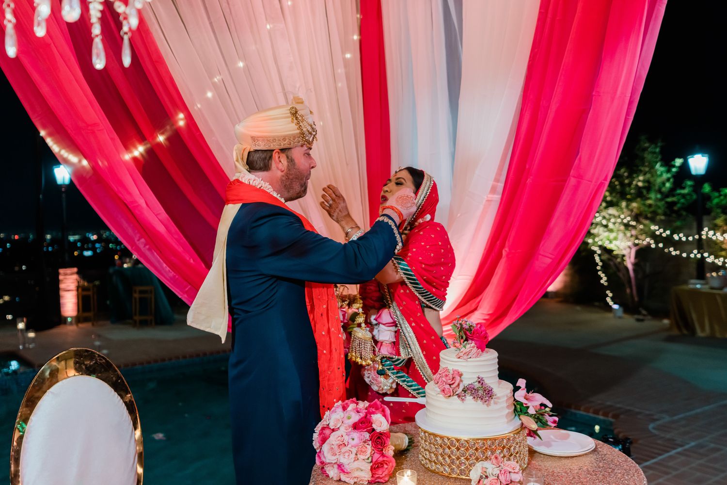 Reception celebration under pink fabric decorations with cake and evening lighting.