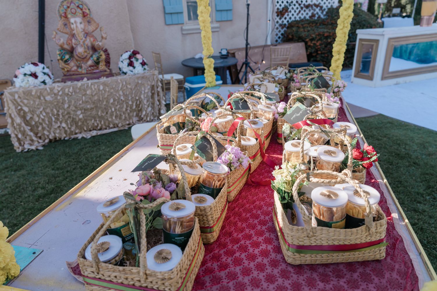 Rustic wedding favors and gift baskets arranged on wooden tables with red and white decor.