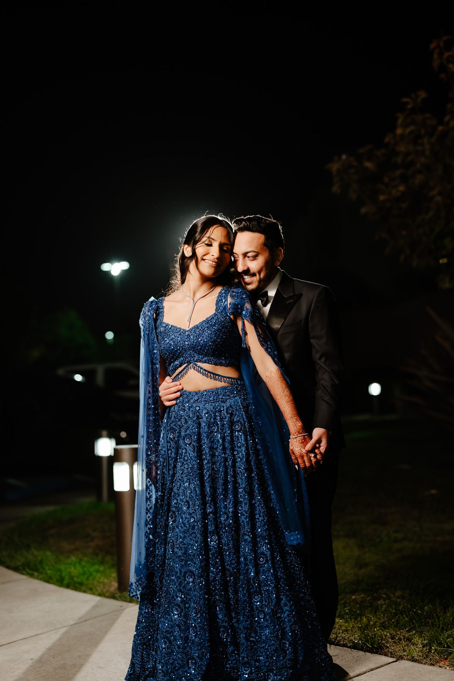 Romantic nighttime couple portrait featuring a sparkling navy blue dress.