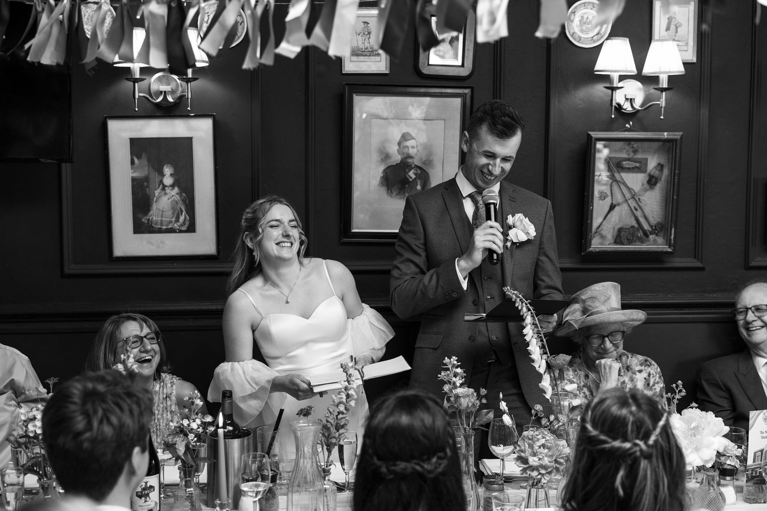 Bride and groom laughing during wedding speeches.