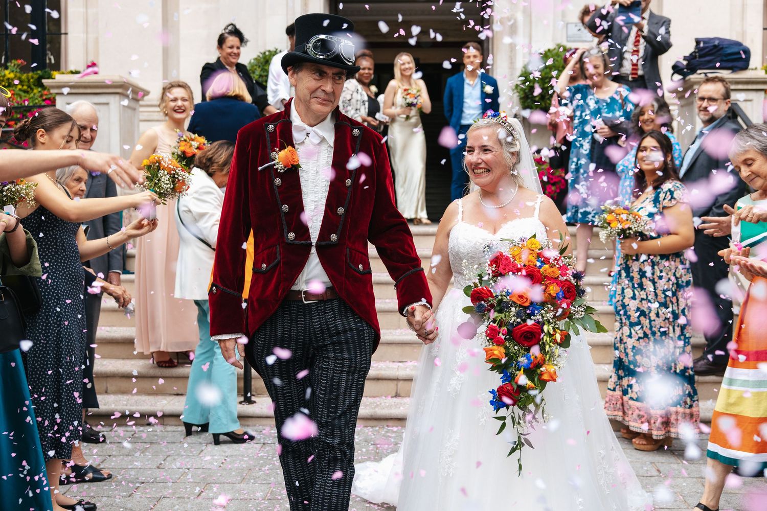 Couple walking through a colourful confetti tunnel outside a London wedding venue.
