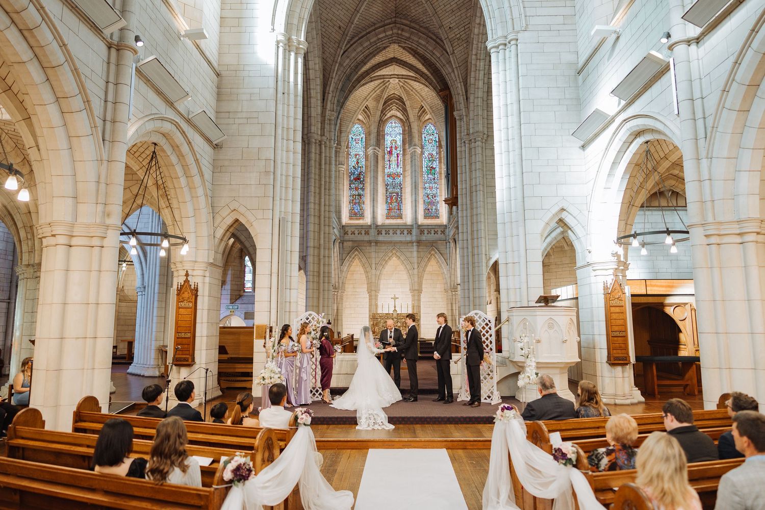 Wedding ceremony in a grand cathedral with soaring stone arches and stained glass windows.