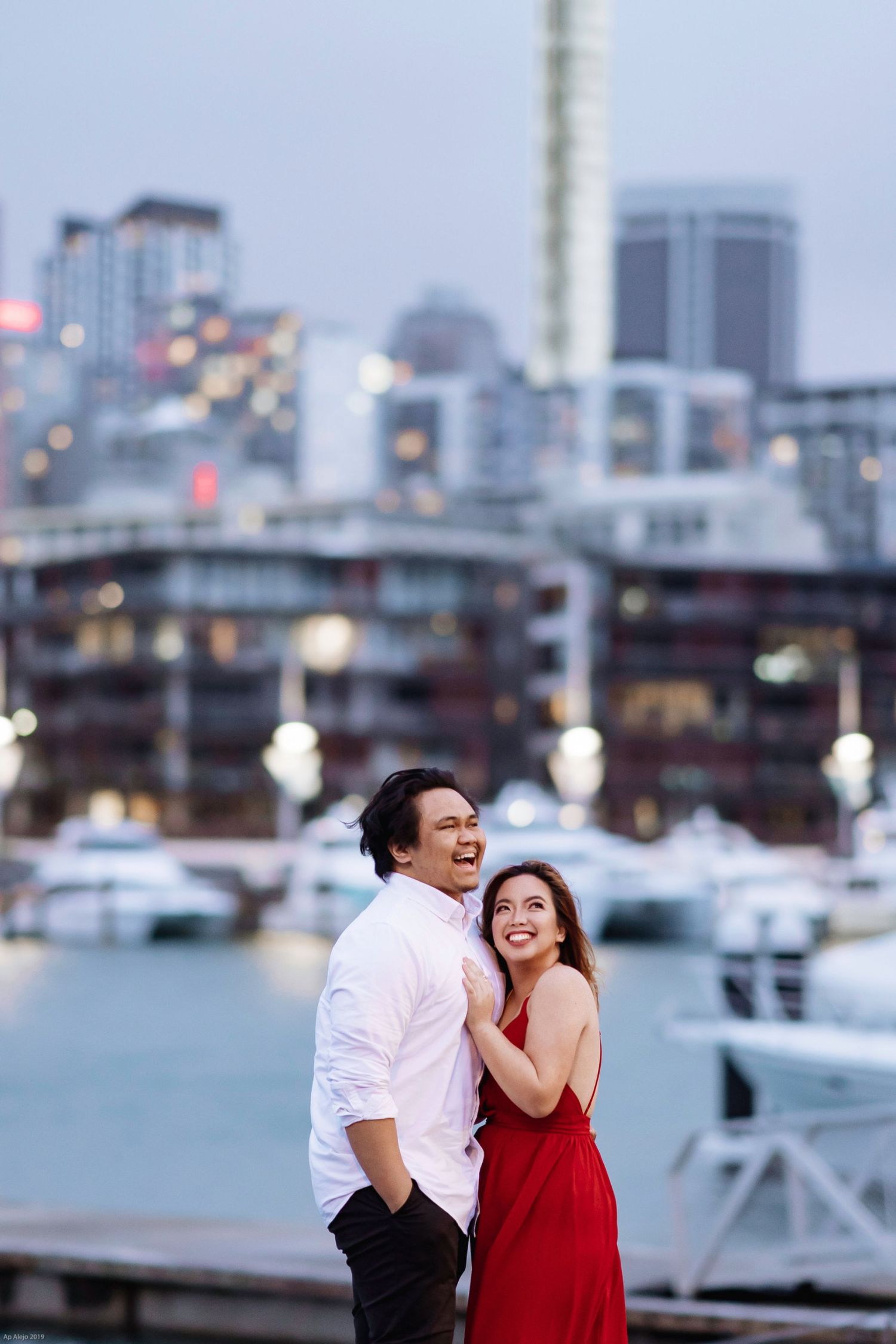 Romantic waterfront scene with city skyline and boats in the background.