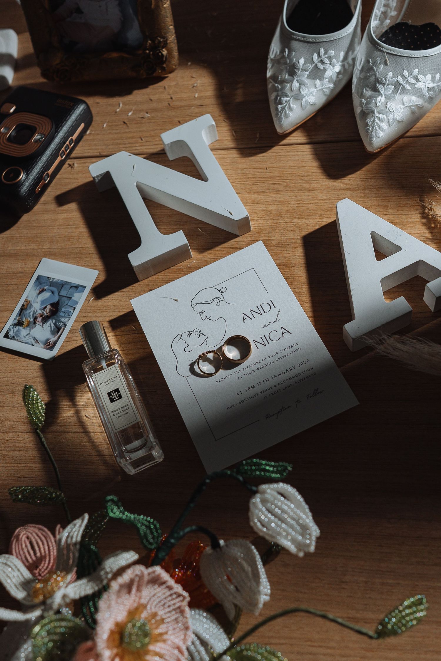 Wedding details including decorative letters and floral arrangements on wooden surface.