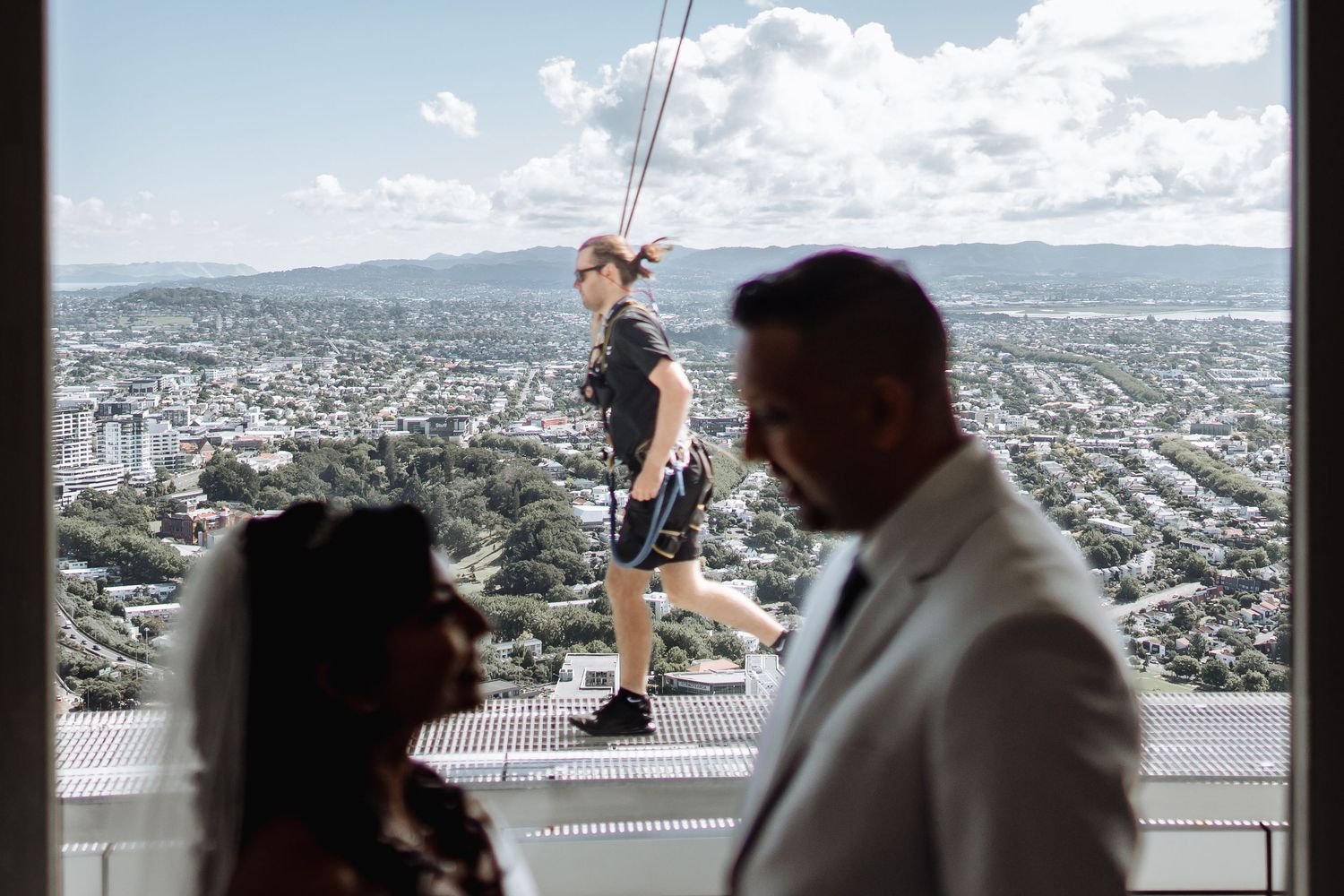A scenic cityscape view from a high vantage point with people silhouetted against the sky.