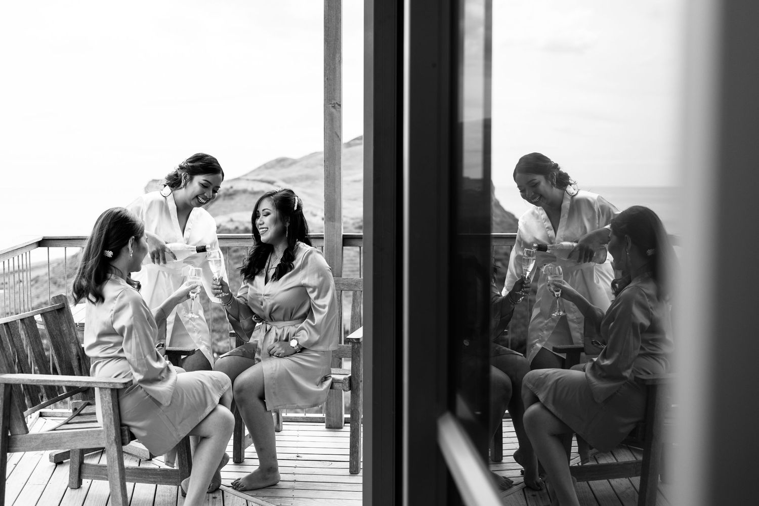 Wedding party gathers indoors by large windows during preparation.