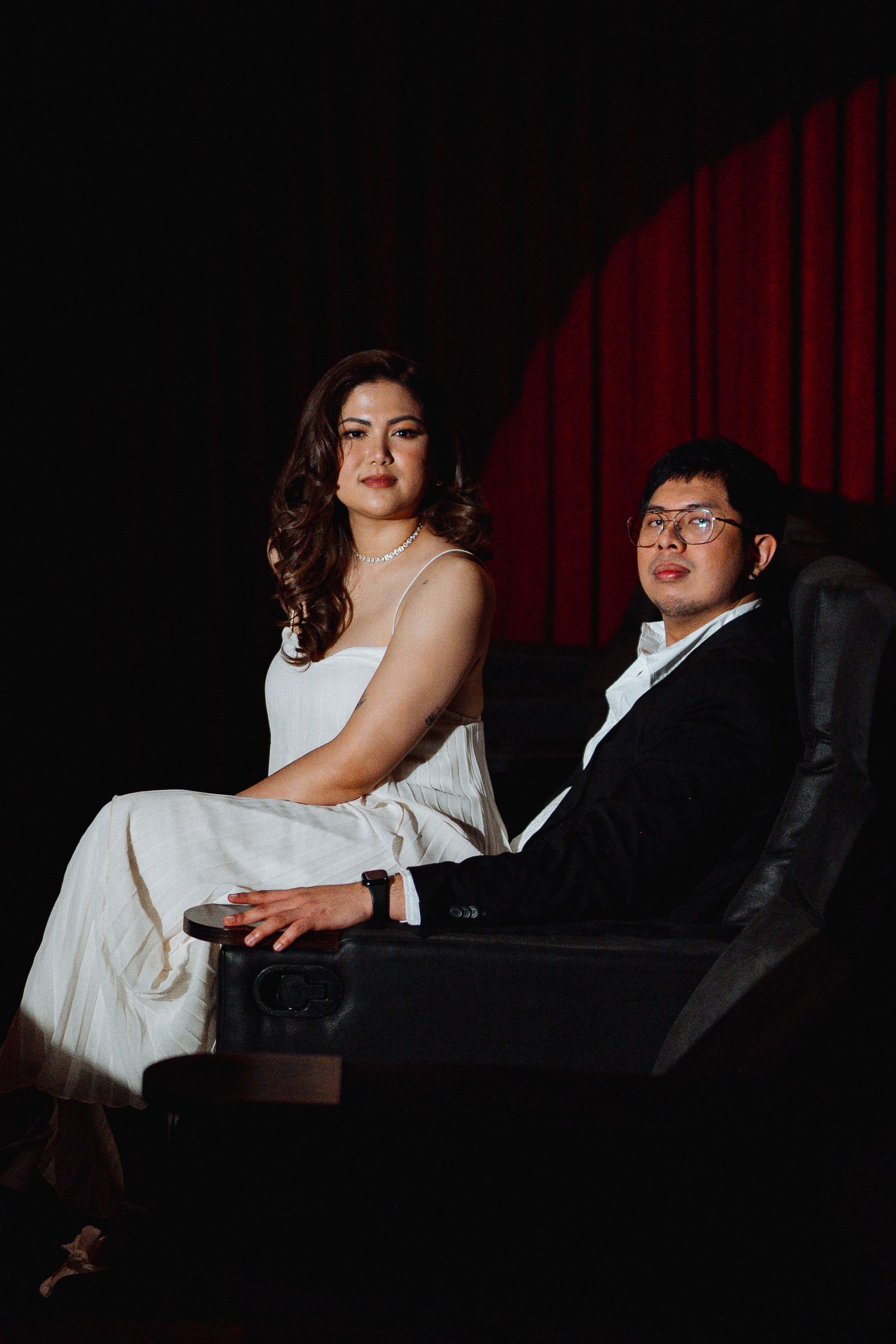 Intimate theater seating portraits with dramatic lighting against red curtain backdrop.