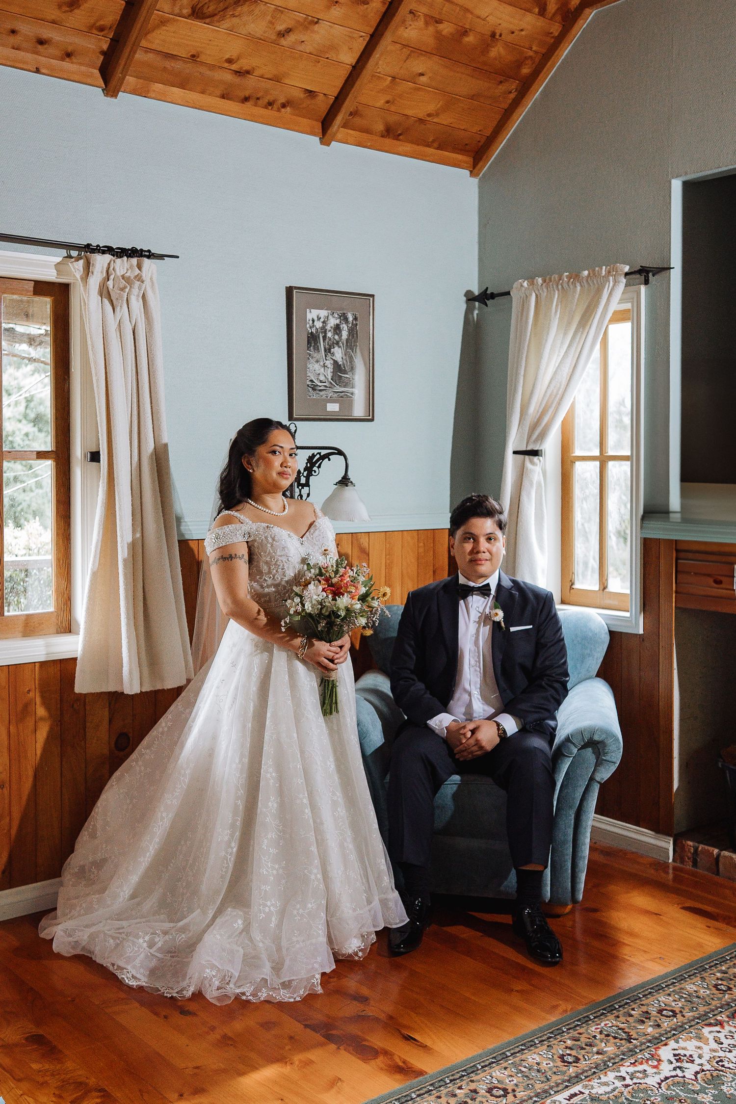 Wedding couple poses in a rustic cabin with wooden walls and hardwood floors.
