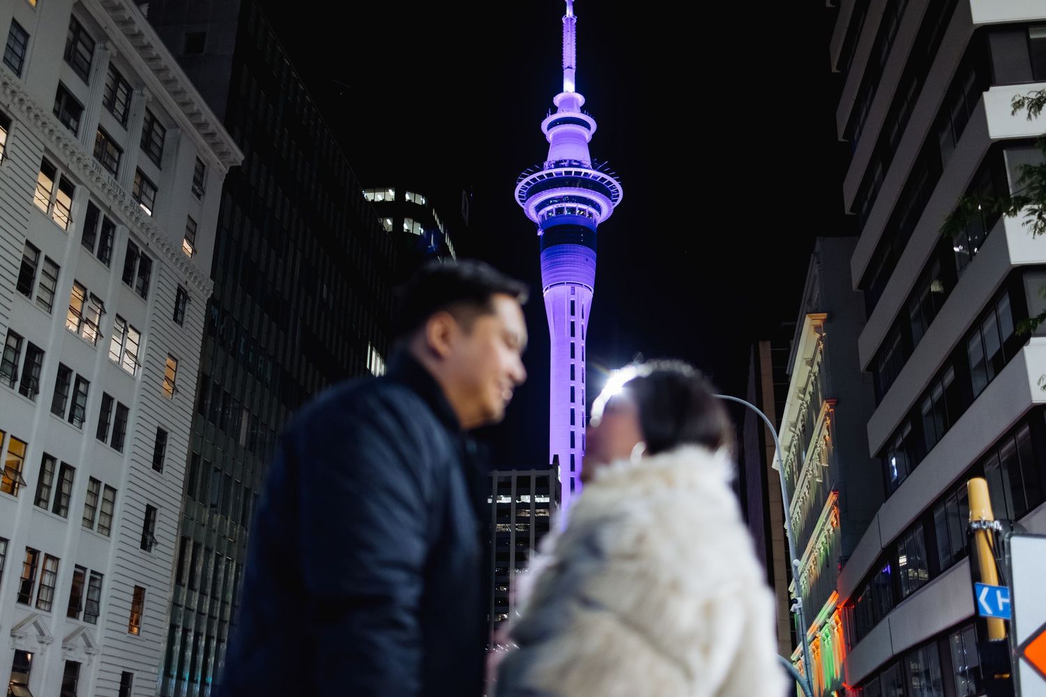 Urban nightscape featuring a glowing blue tower with city buildings.