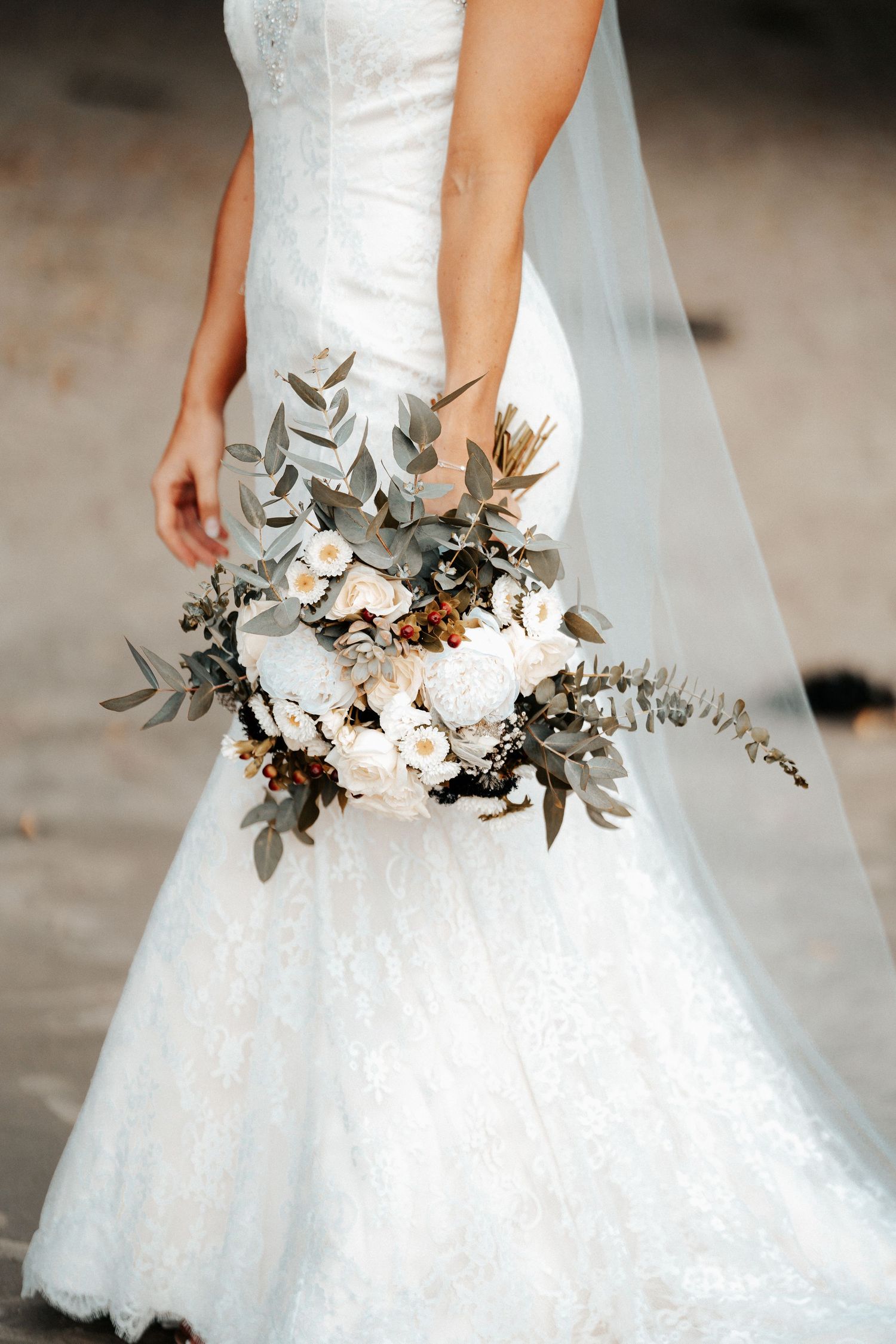 Close-up of a white wedding dress with delicate floral and eucalyptus details.