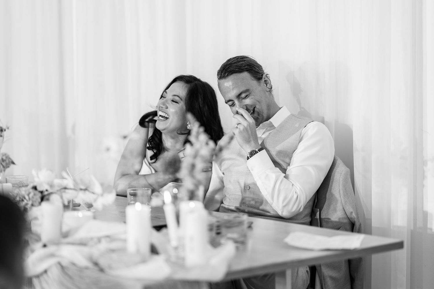 Wedding reception candid moments captured in black and white with elegant white backdrop.