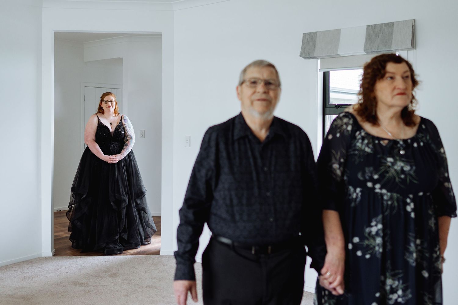 People dressed in formal black attire standing together in a bright white room.
