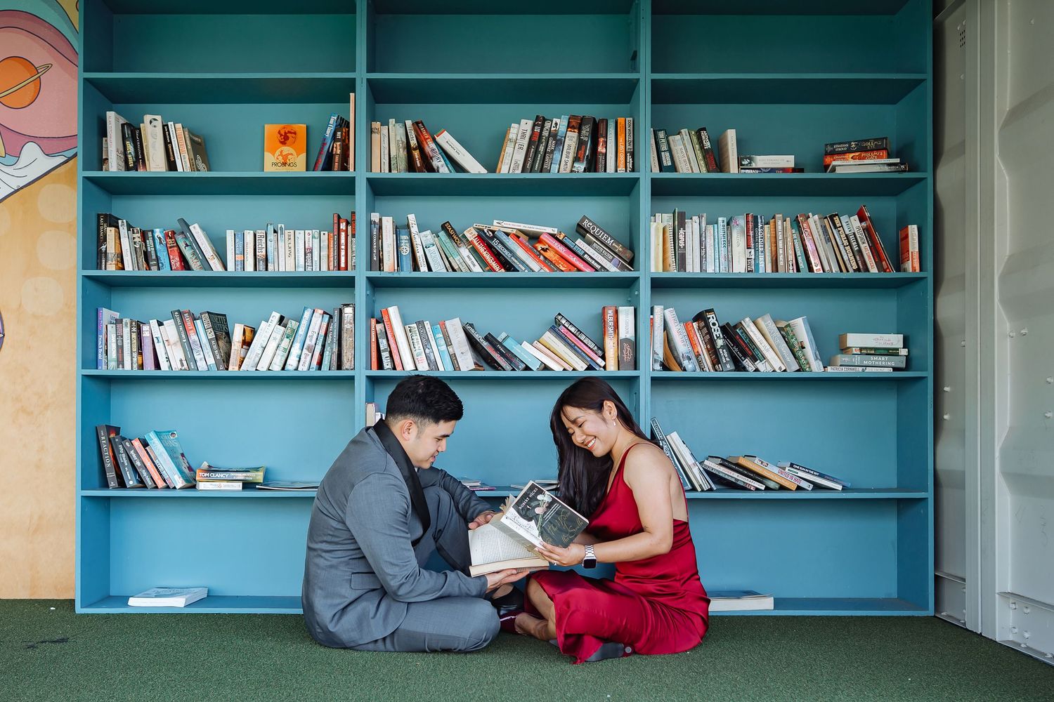 Library interior with turquoise shelves filled with books along a long wall.