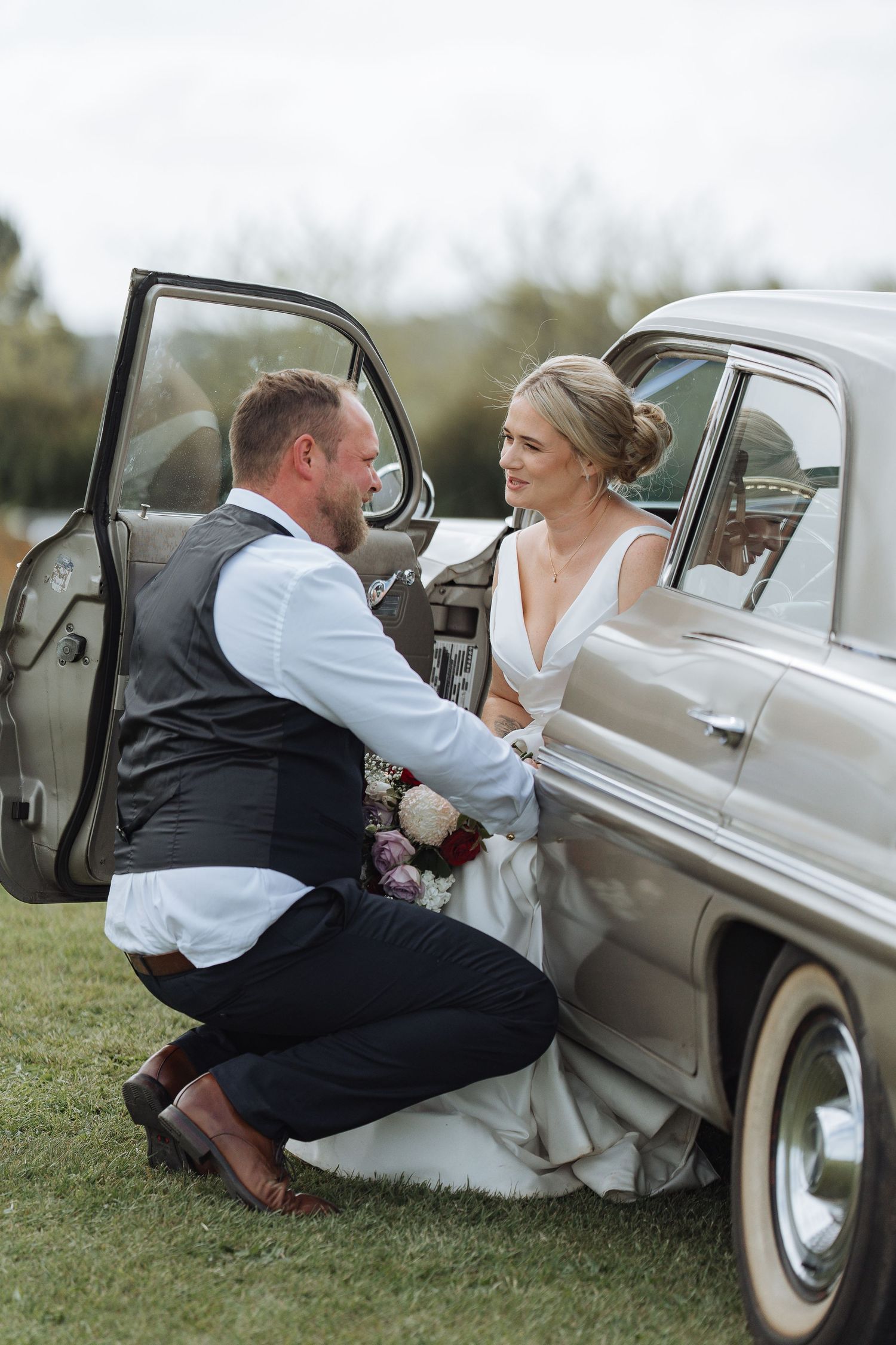 A sweet moment by a vintage car as a couple shares a moment during their wedding day.