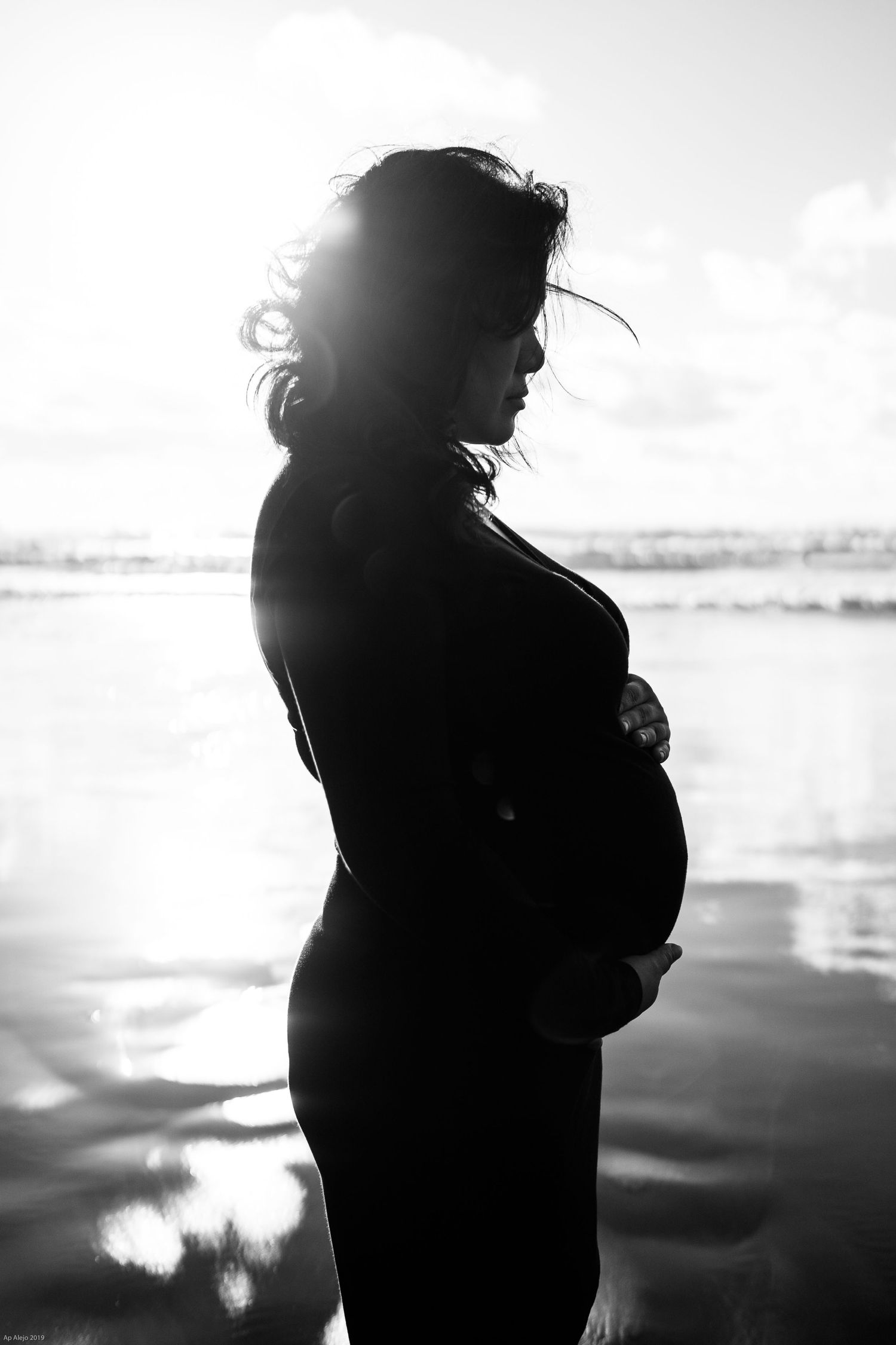 Silhouette portrait against bright sky with dramatic backlighting.