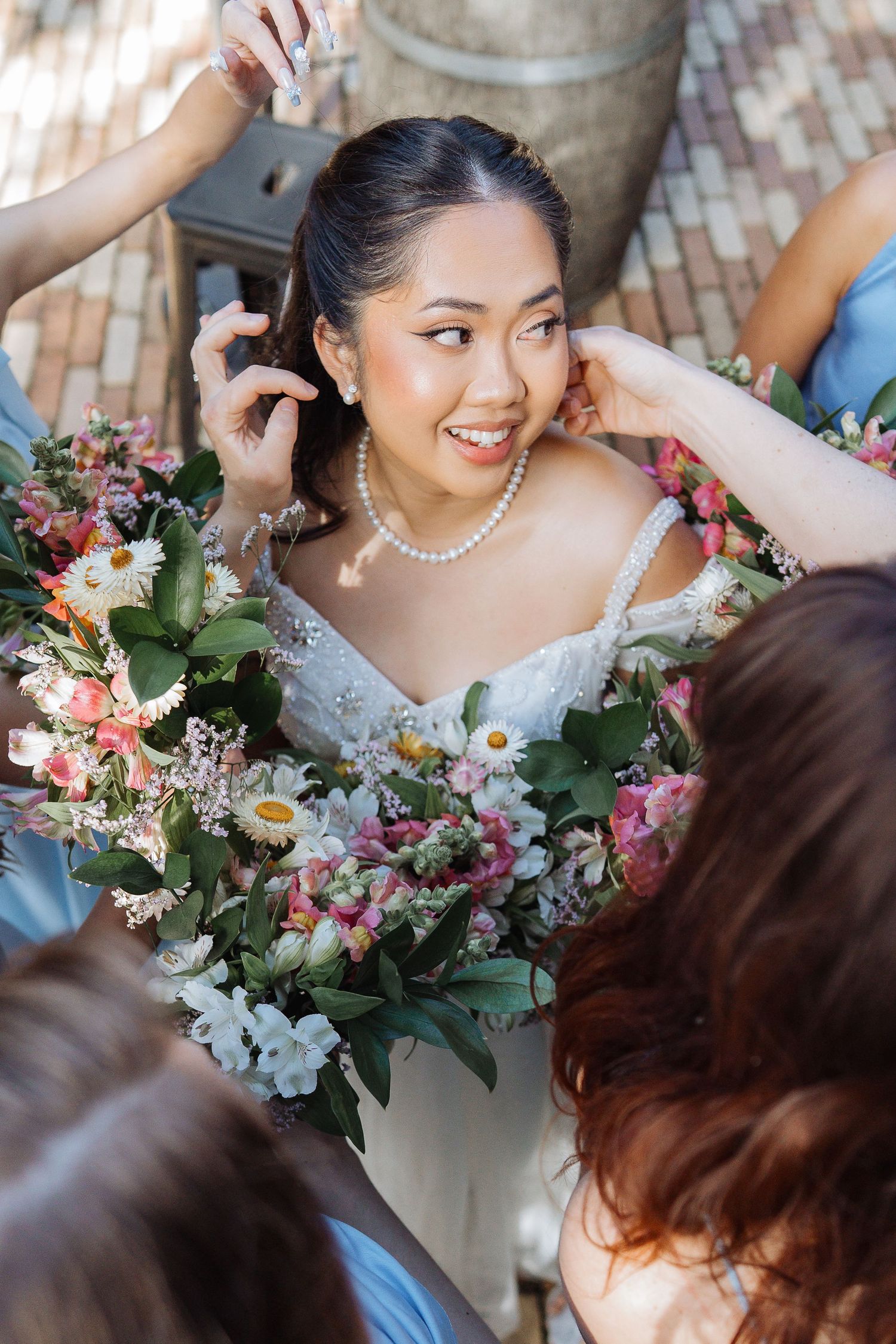 A wedding bouquet with pink and white flowers is held against a white dress.