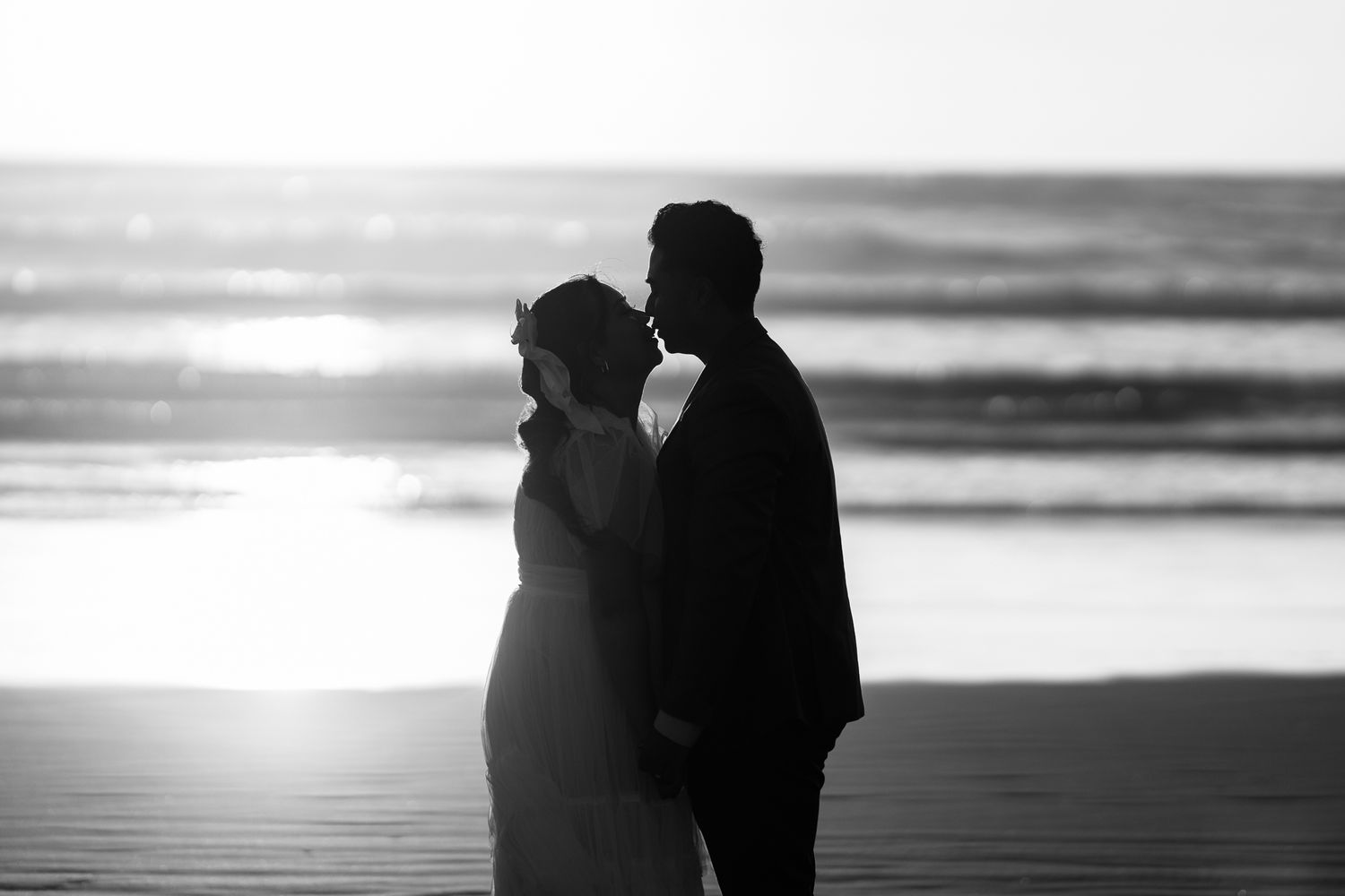 Silhouettes of a couple walking on a beach at sunset with dramatic lighting.