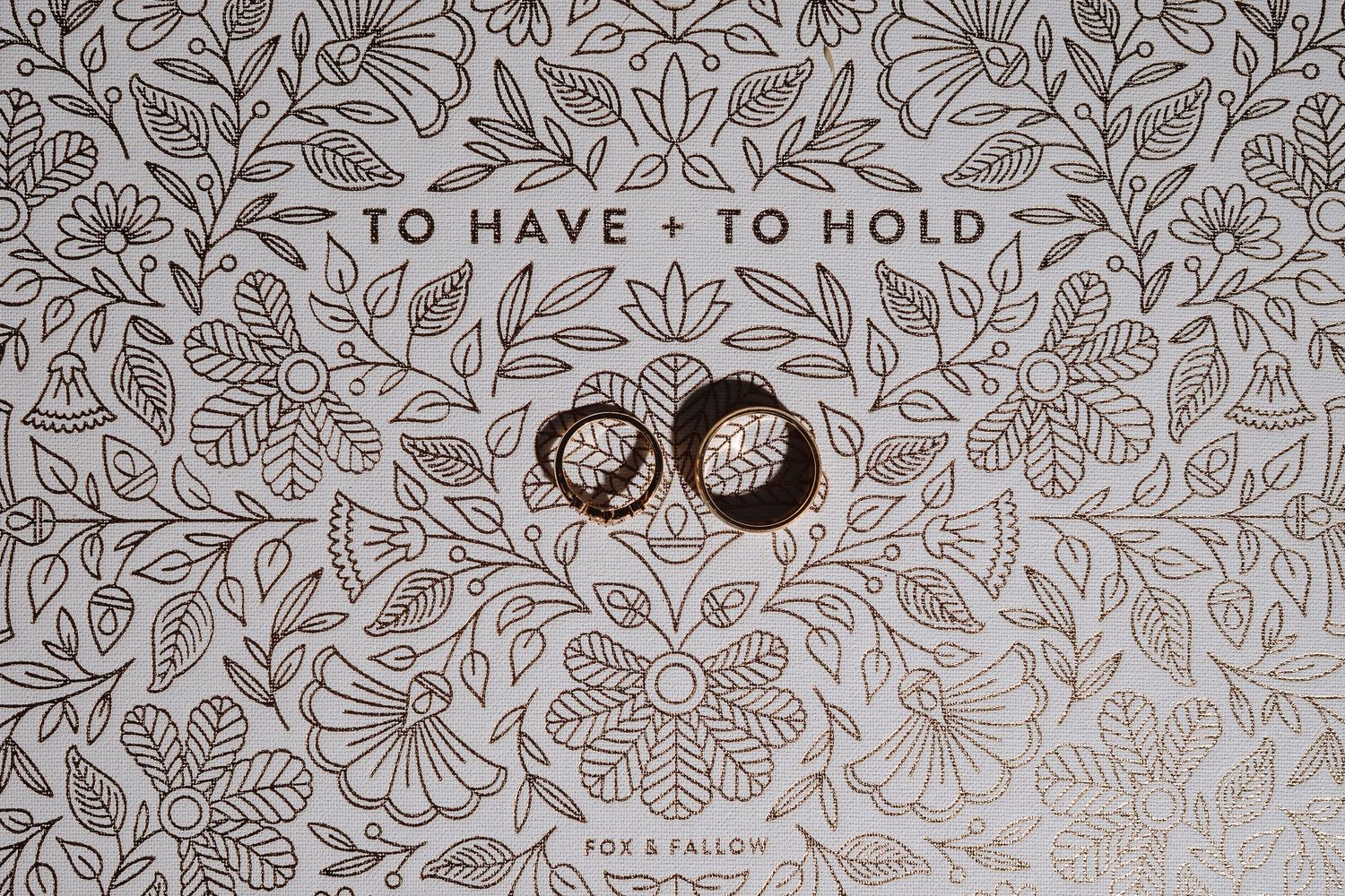 Decorative floral pattern in brown and beige tones with text 'TO HAVE + TO HOLD' visible.