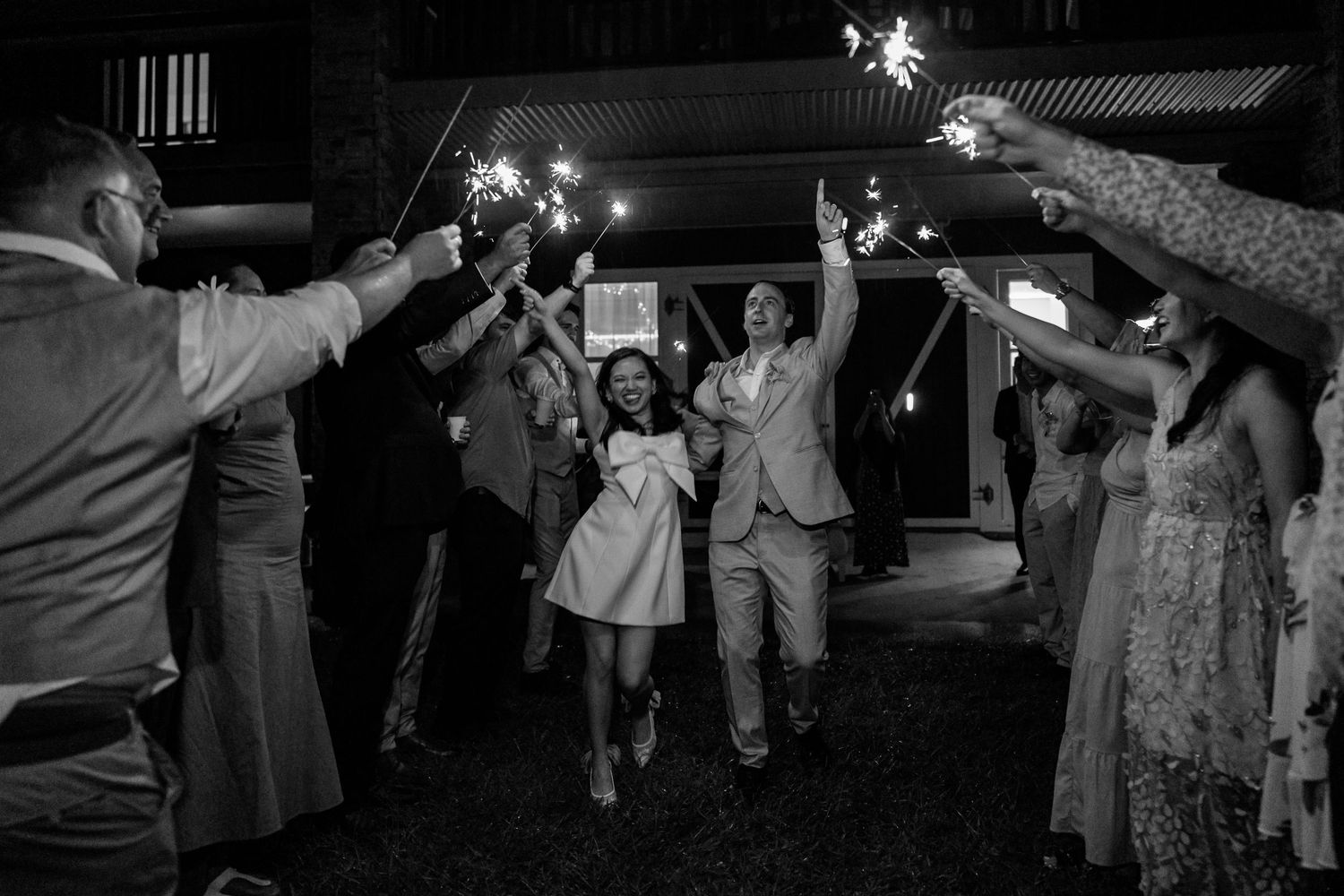 Wedding guests dancing at night with sparklers creating magical light trails in the darkness.