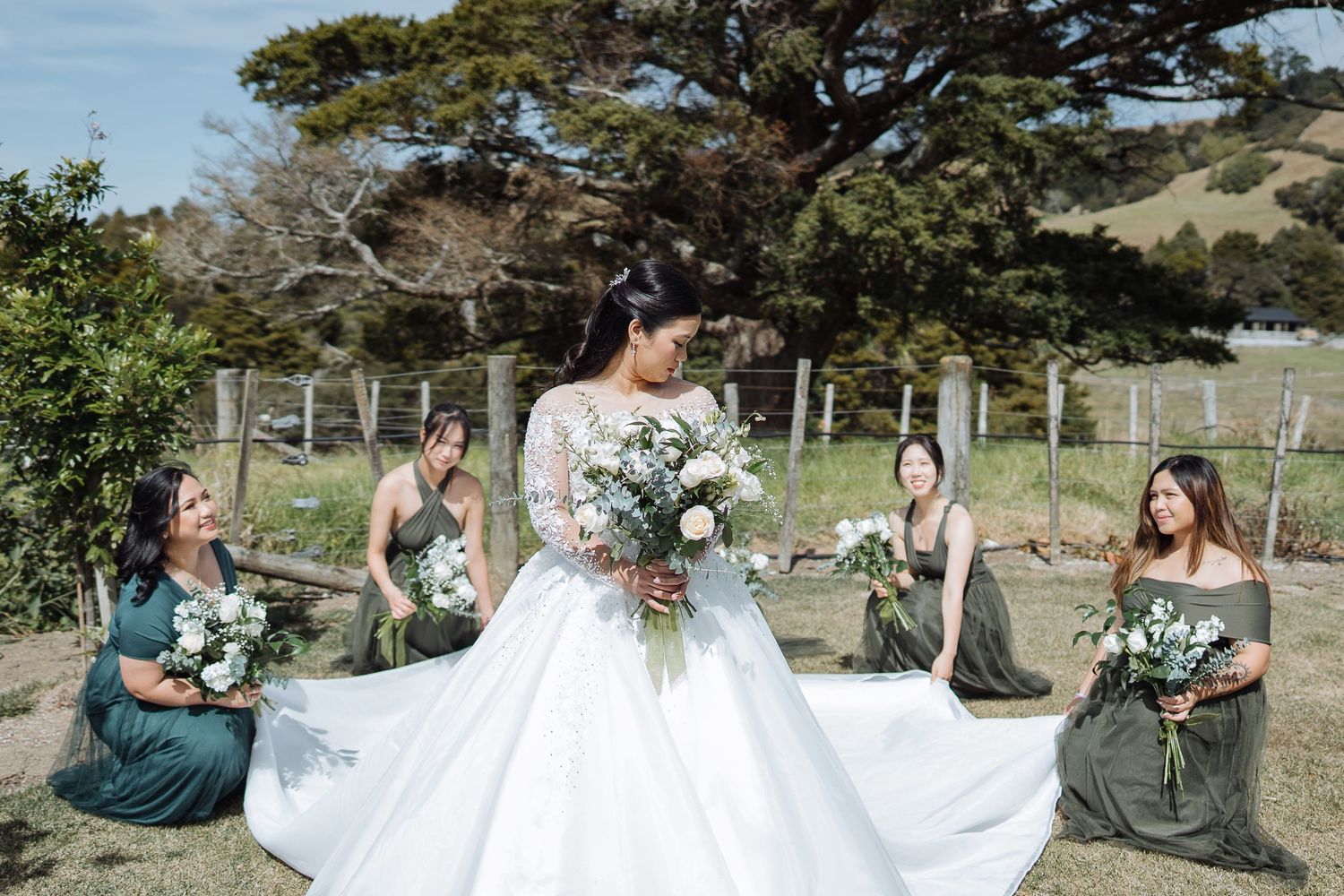 Bridal party in emerald green dresses posing outdoors.
