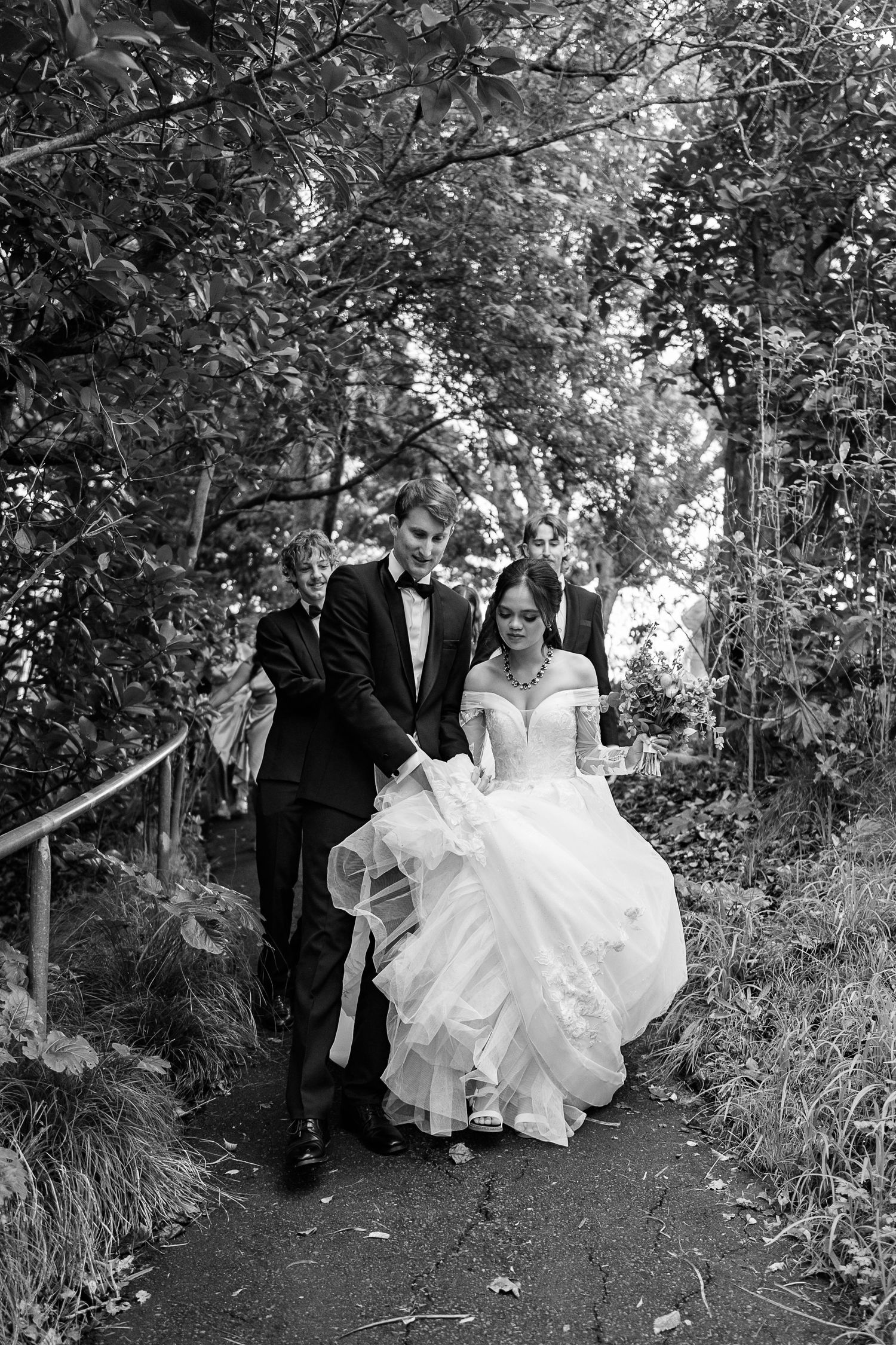 Wedding couple walking through a lush garden path surrounded by greenery.