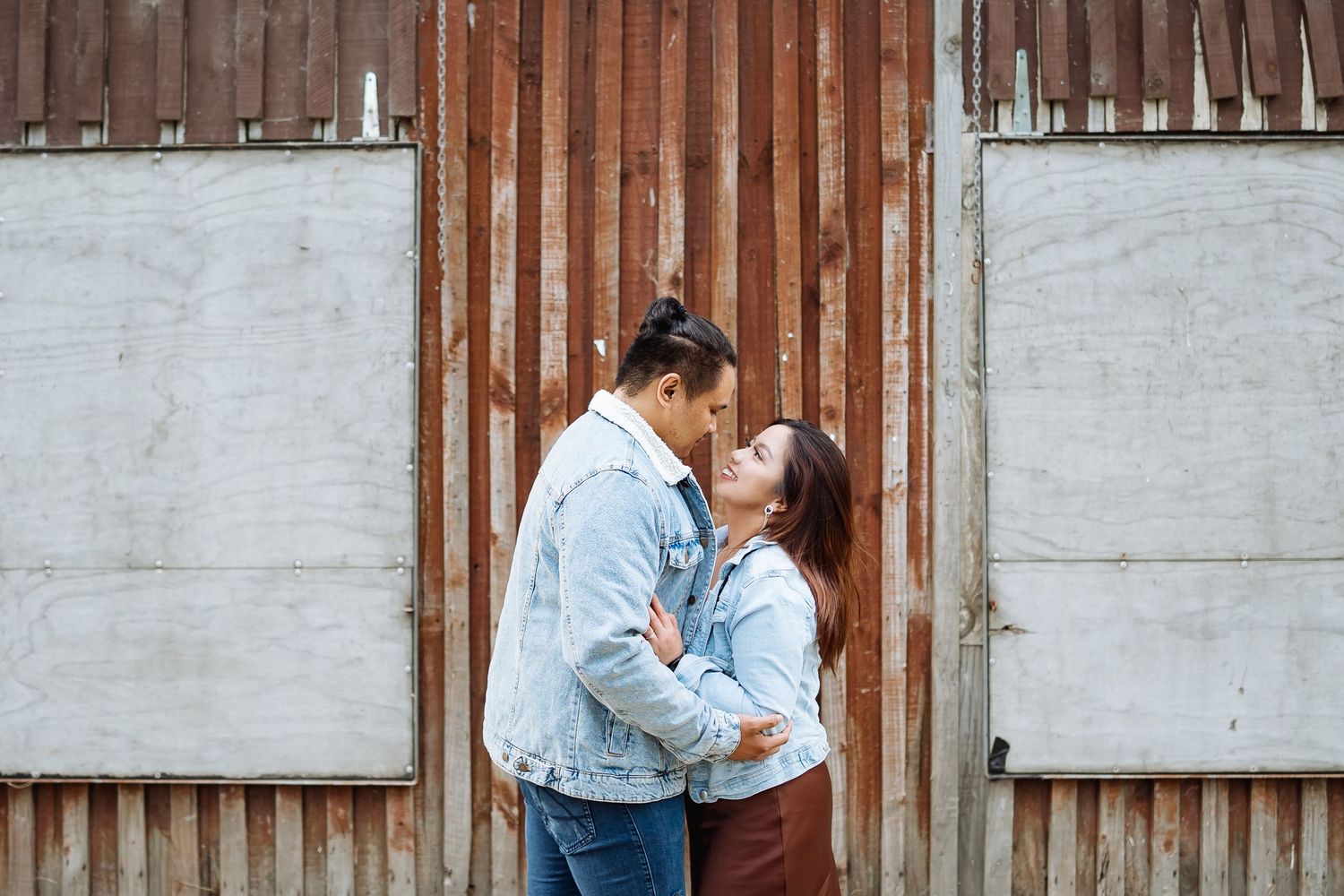 Couple embracing against rustic wooden wall background.